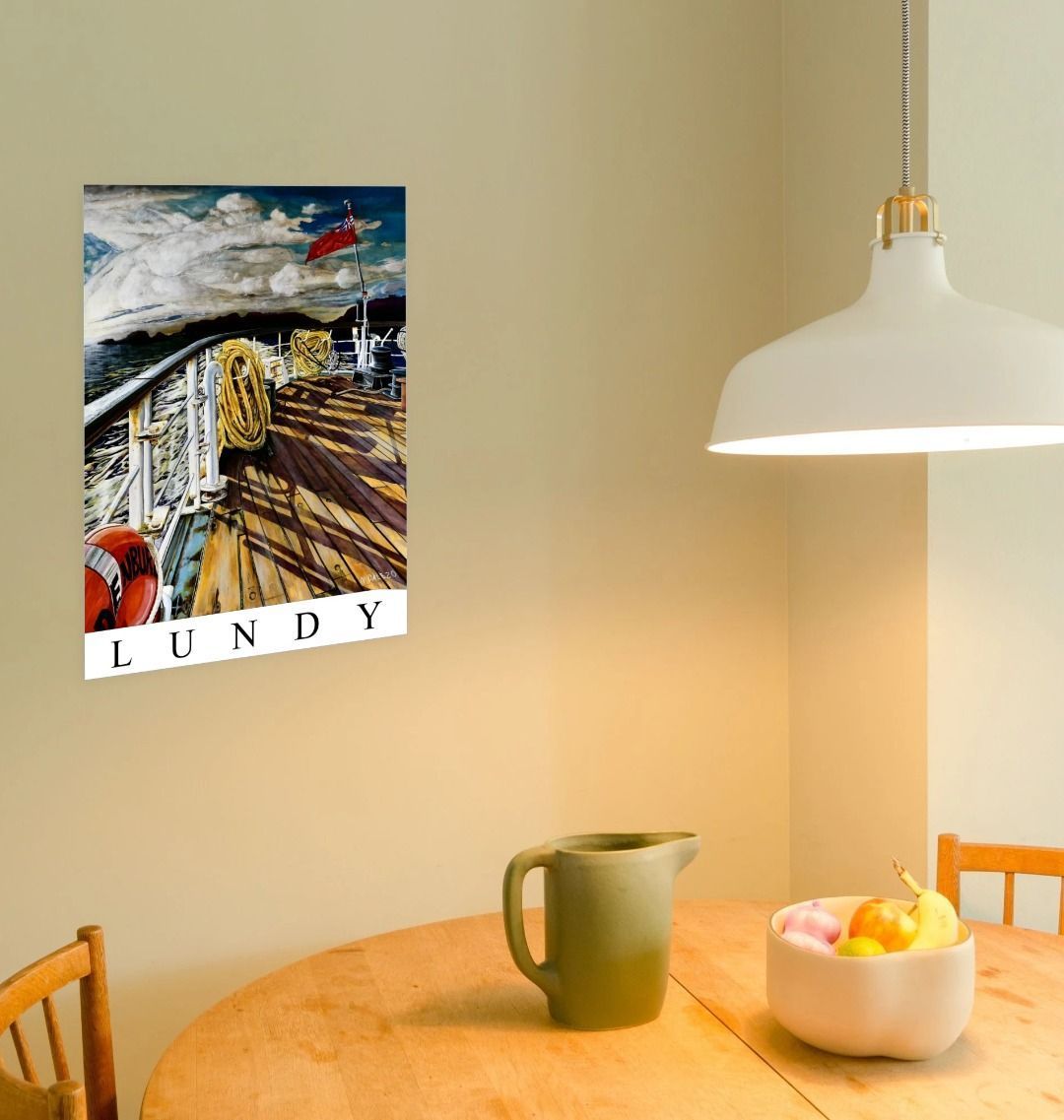 Image of a Large Art Print (A3 size) featuring a copy of the painting 'Diminishing Returns From Lundy' by Nick Dale, with the word 'Lundy' written beneath it. As displayed on a wall next to a dining table. The print depicts the stern of the ship MS Oldenburg as it returns to the mainland from Lundy Island, Devon. As the sun goes down it casts long shadows on the deck. whilst the flag flutters in the breeze. The Silhouette of the island can be seen diminishing into the background.