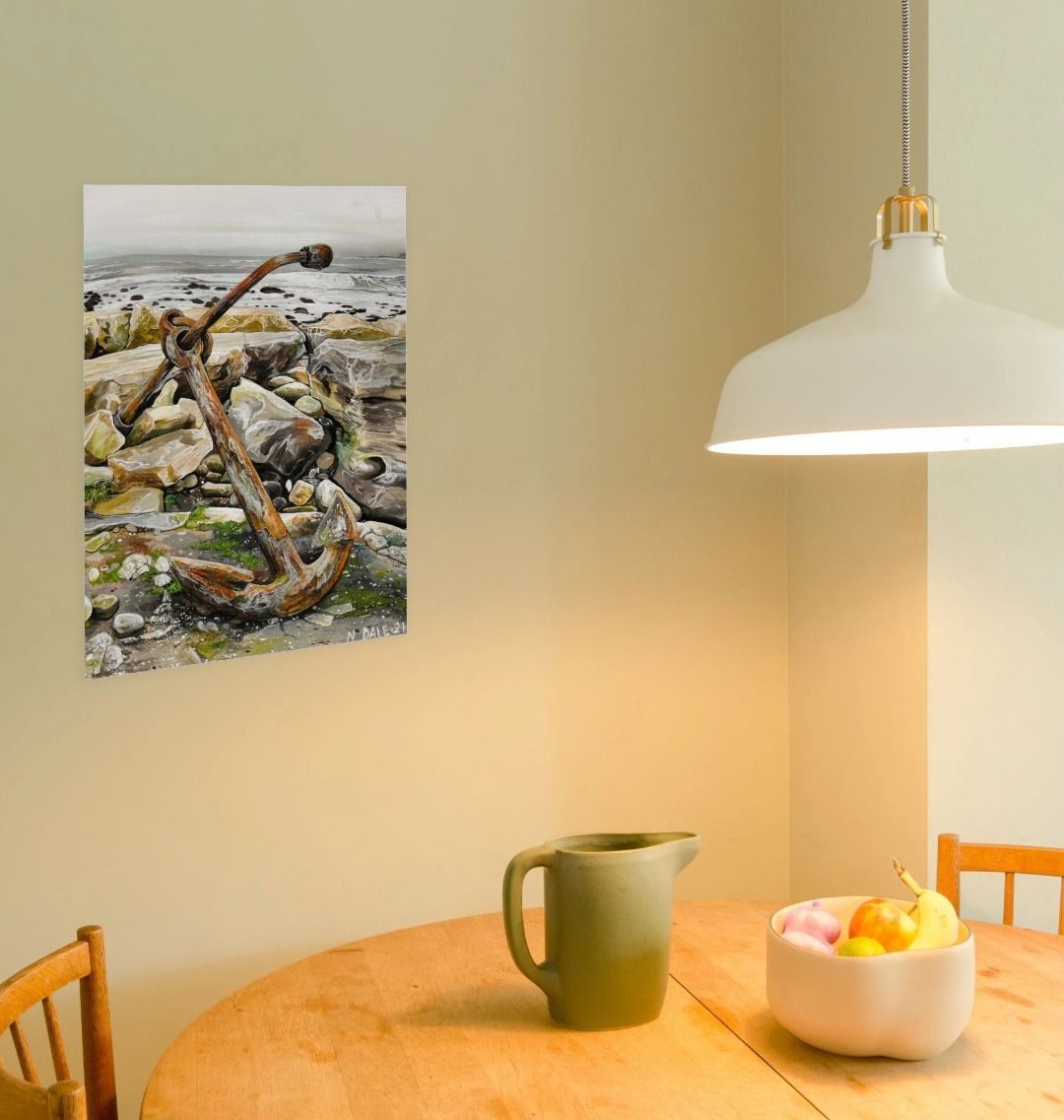 Image of a Large Art Print (A3 size) featuring a copy of the painting 'The Sea Anchors The Land To The Sky' by Nick Dale. As displayed on a wall next to a dining table. The print depicts an old anchor lying at rest under a leaden sky upon the foreshore at Chapman's Pool, near Worth Matravers, Dorset.