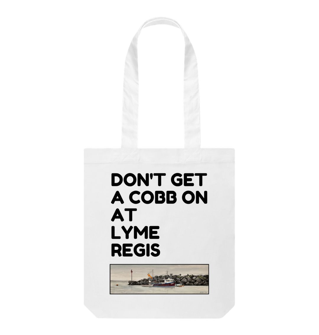 Image of a White Tote Bag featuring a copy of the painting 'End Of The Line' by Nick Dale with the slogan 'Don't Get A Cobb On At Lyme Regis' written above it. The bag depicts a fisherman preparing his catch for unloading at Lyme Regis as the birds line up on the breakwater and patiently await their turn to feed.