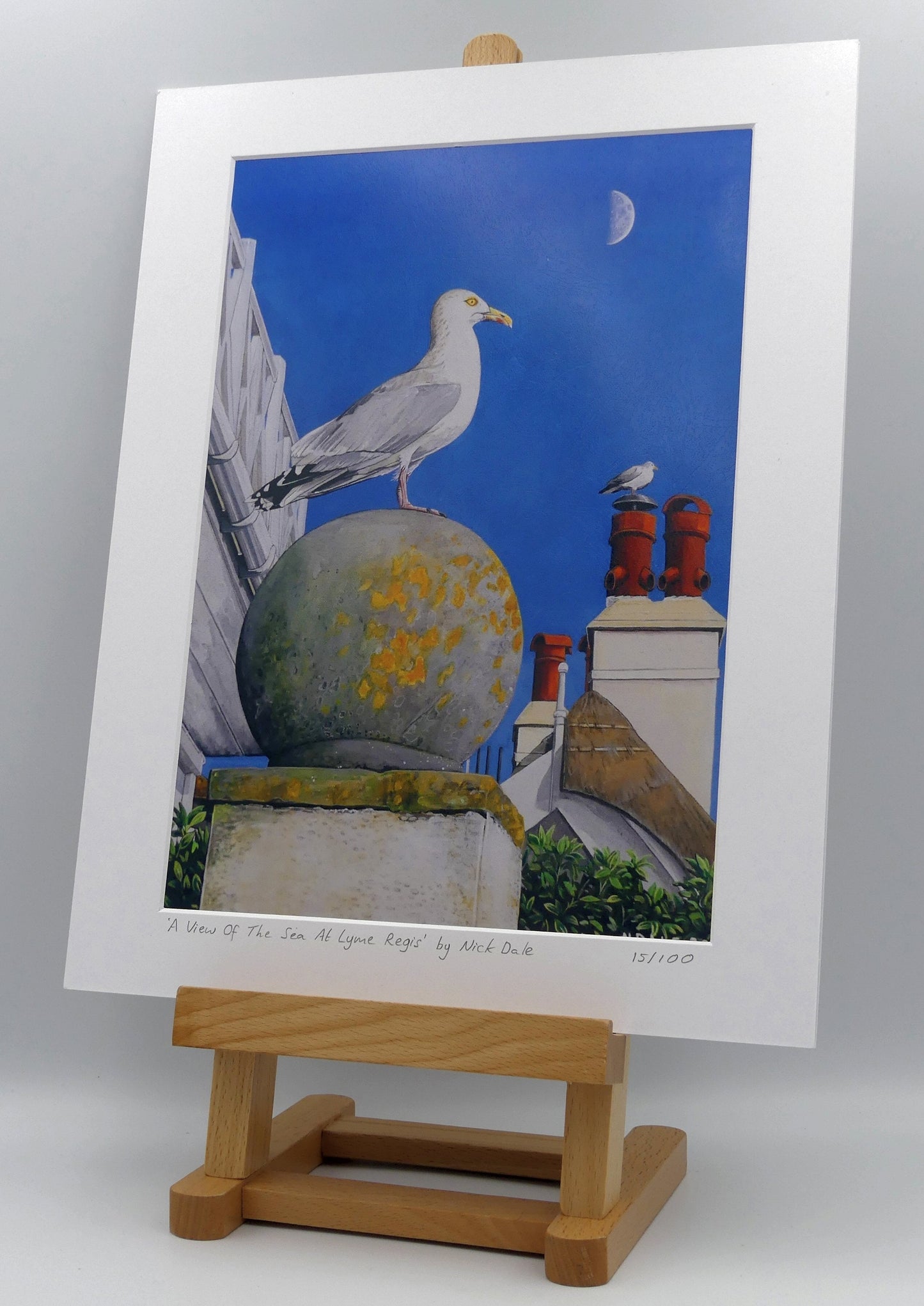Image of Medium Art Print featuring a copy of the painting 'A View Of The Sea At Lyme Regis' by Nick Dale. The print depicts a gull and buildings along Marine Parade, Lyme Regis. The print is situated on a small easel.