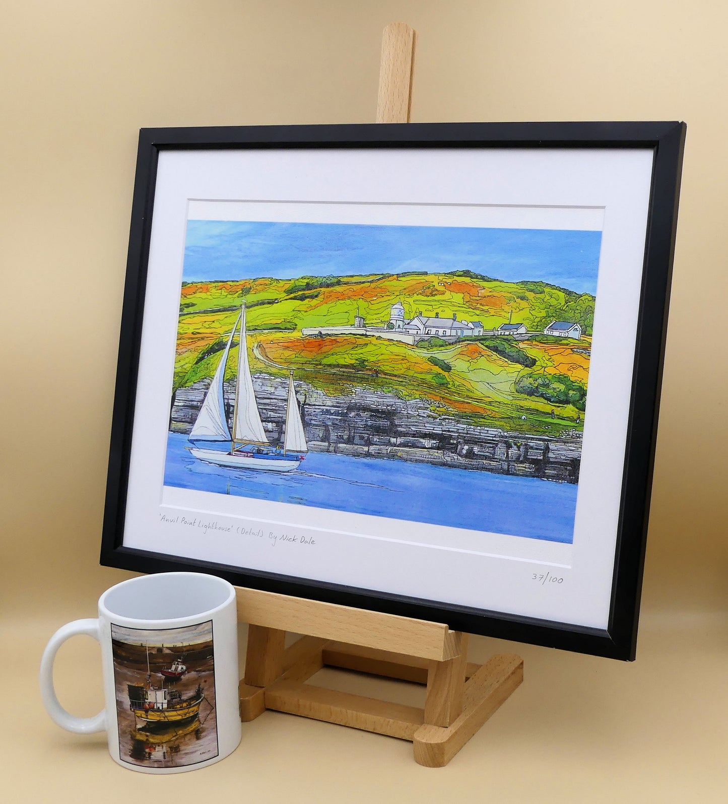 Image of a Medium Art Print featuring a copy of the painting 'Anvil Point Lighthouse' by Nick Dale. The print depicts the part of the original painting showing the Anvil Point Lighthouse at Durlston Country Park, Swanage. Based on the view from the paddle-steamer Waverley. The print is situated on a small easel in a black frame next to a mug.