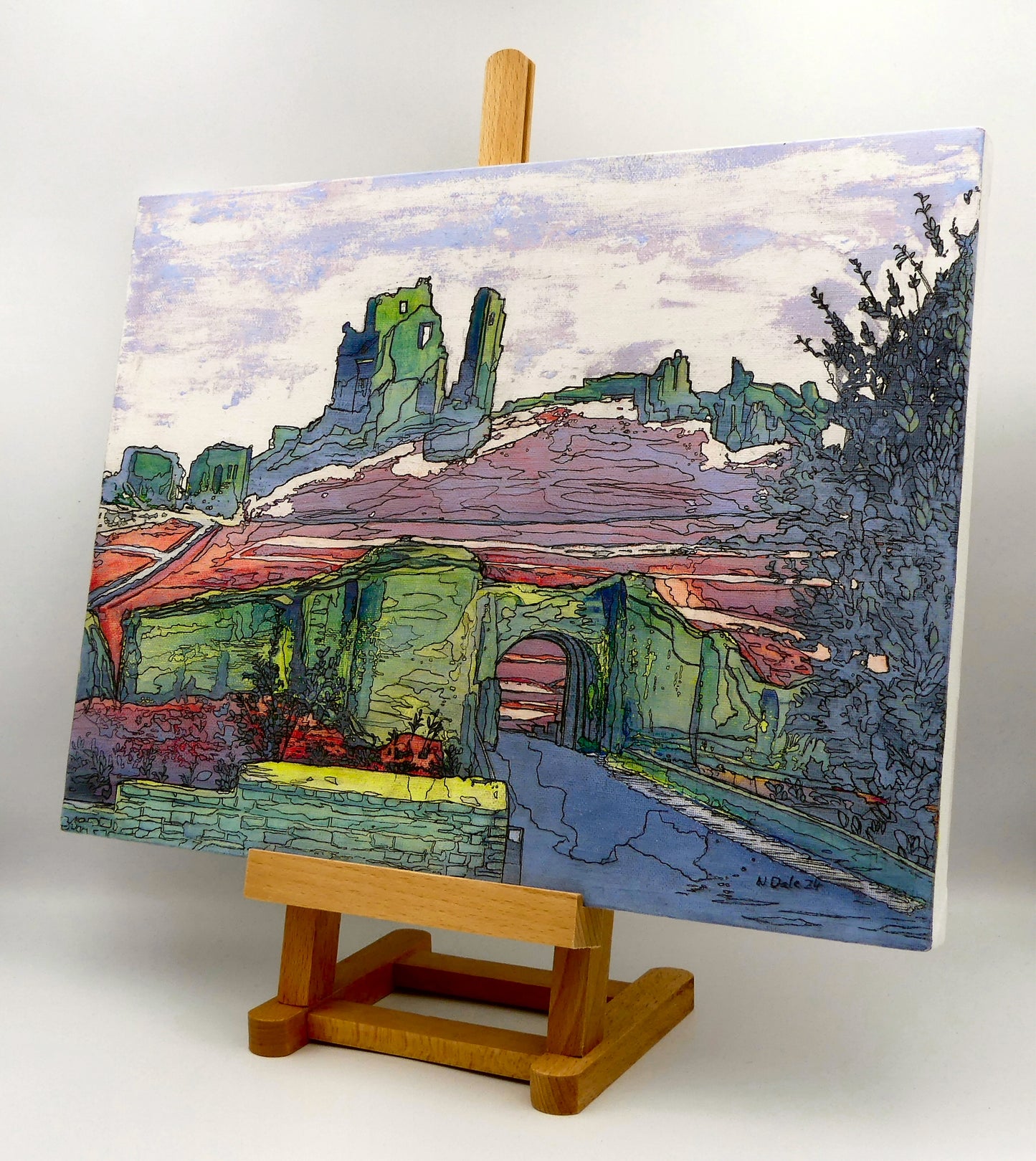 Image of the original painting 'Corfe Castle Outer Gatehouse' by Nick Dale on an easel. The painting depicts the slighted outer gatehouse of Corfe Castle in the village of Corfe Castle, Dorset. Beyond it can be seen the castle's south-west gatehouse and keep on top of the central hilltop.
