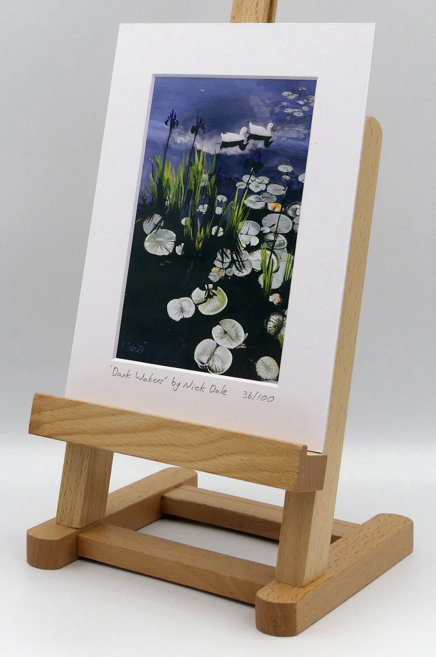 Image of a Small Art Print featuring a copy of the painting 'Dark Waters' by Nick Dale. The print depicts lily pads, irises and ducks on a pond at Knightshayes Court, Devon. The print is situated on a small easel.