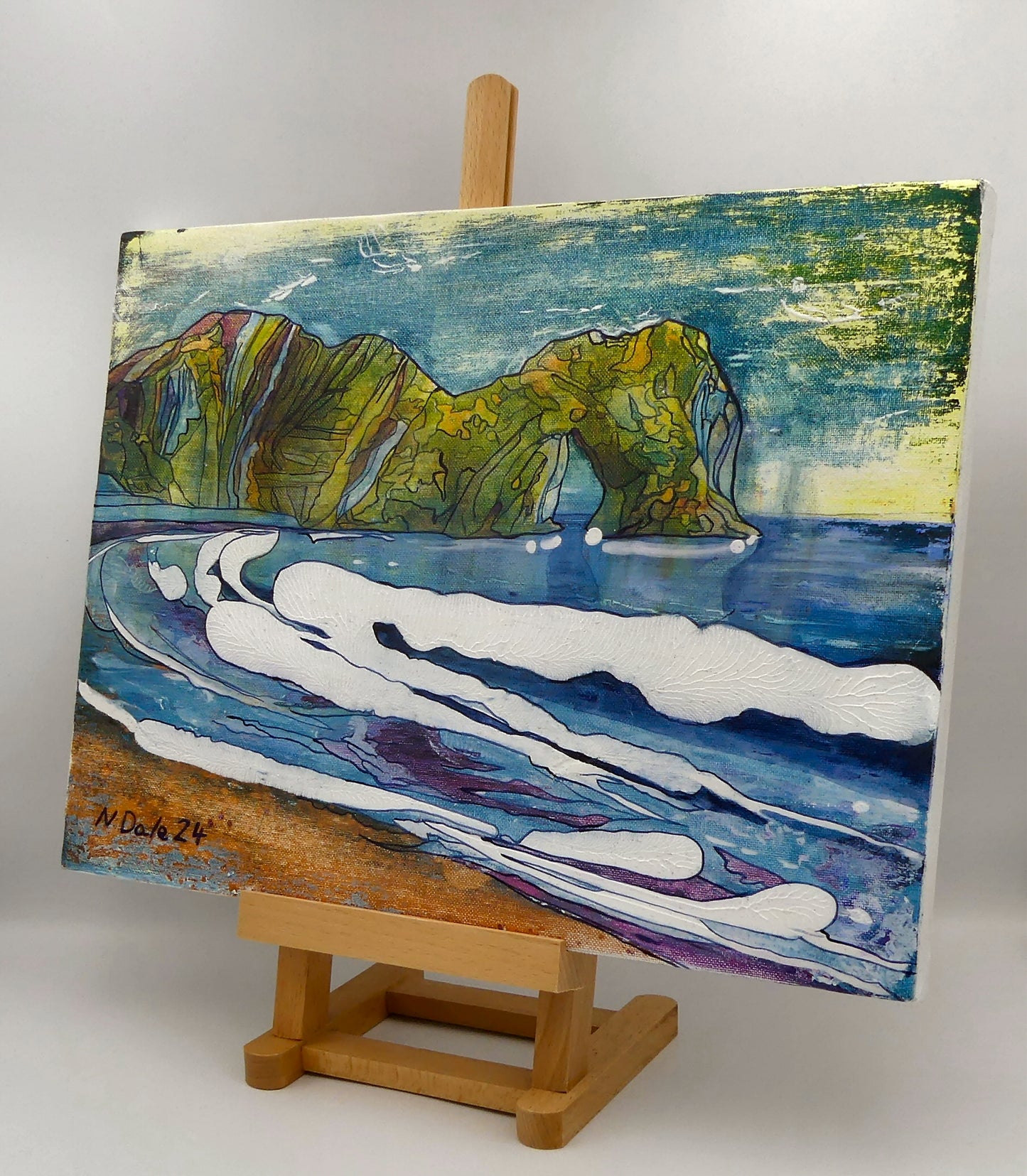 Image of the original painting 'Durdle Door Arch (Version 6)' by Nick Dale on an easel. The scene depicts the famous Dorset limestone arch landmark ‘Durdle Door’, as seen from the beach.