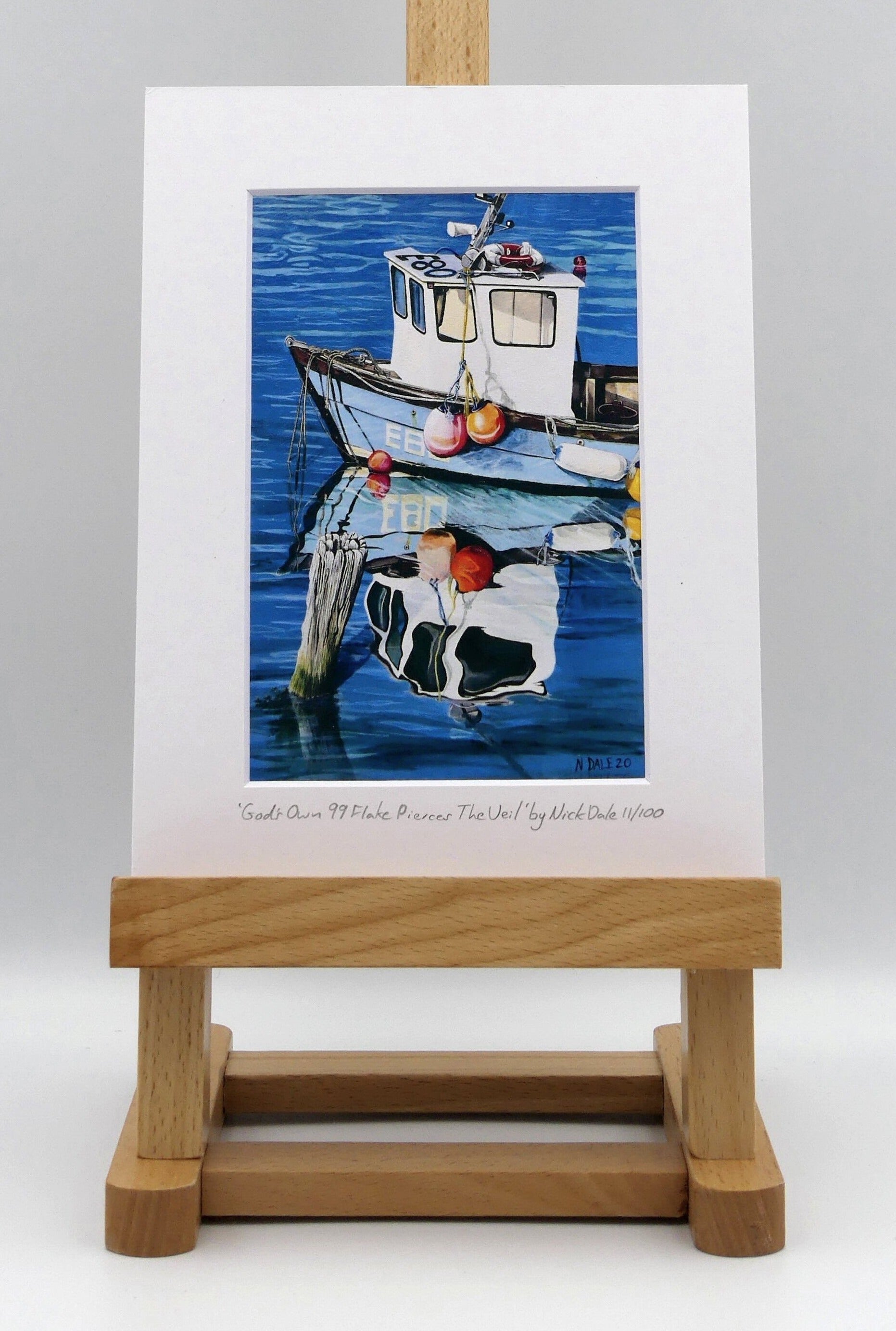 Image of a Small Art Print featuring a copy of the painting 'God's Own 99 Flake Pierces The Veil' by Nick Dale. The print depicts a fishing boat at rest within the harbour of Lyme Regis, Dorset. The title is based on the similarity of the wooden pile to a chocolate flake as inserted into an ice cream cone. This seemed appropriate given the draw of the town to tourists. The print is situated on a small easel.