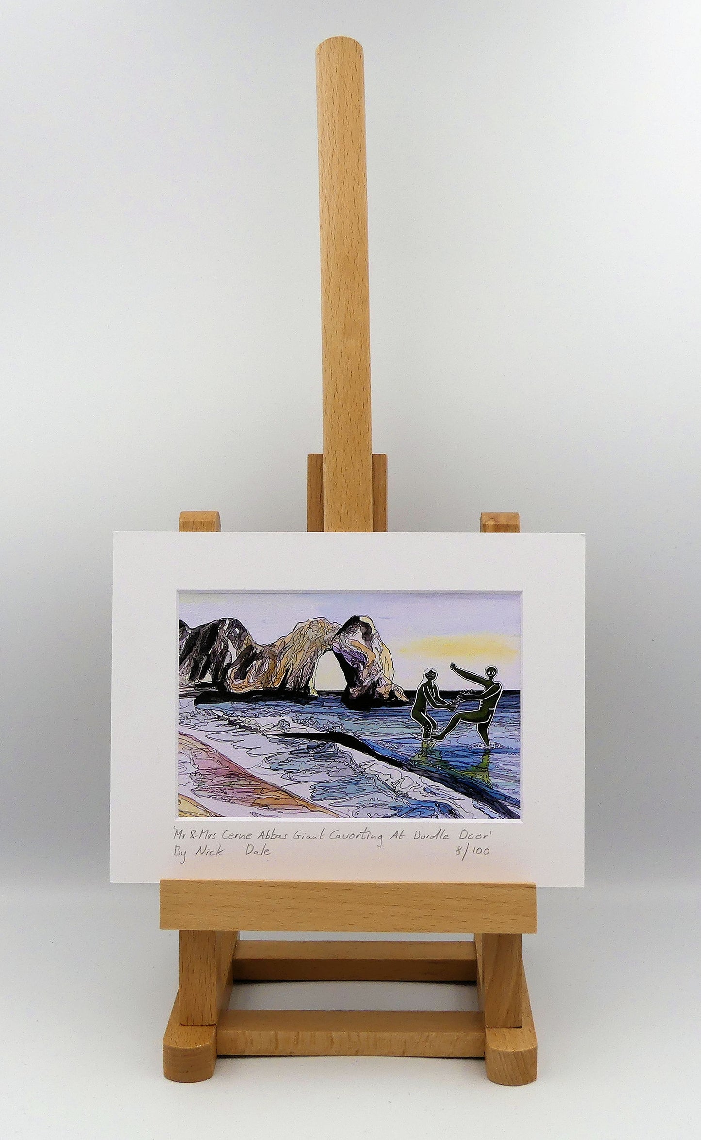 Image of a Small Art Print featuring a copy of the painting 'Mr & Mrs Cerne Abbas Giant Cavorting At Durdle Door' by Nick Dale. The scene imagines the future Mr & Mrs Cerne Abbas Giant's first date at Durdle Door; where they cavort in the water in front of the famous Dorset landmark. The print is situated on a small easel.