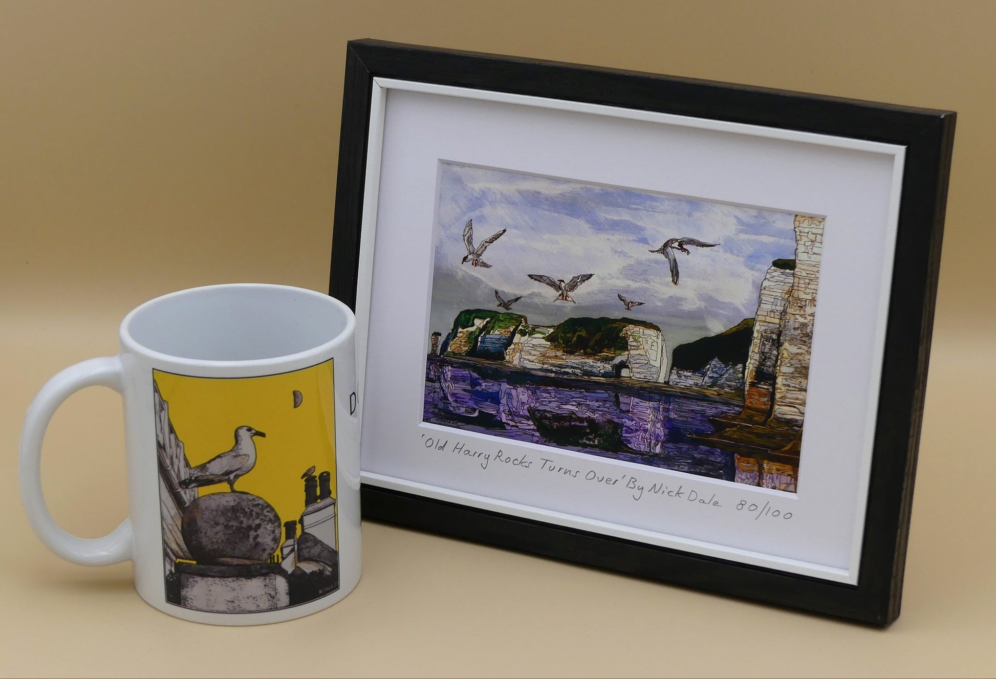 Image of a Small Art Print featuring a copy of the painting 'Old Harry Rocks Turns Over' by Nick Dale. The print depicts the view on a walk in March 2025 when the tide was completely out so I could walk to Old Harry Rocks. I never realised that that was ever possible. I had to add in the water when I painted it afterwards as it was completely missing. Turns also added to taste. The print is situated in a black frame next to a mug.