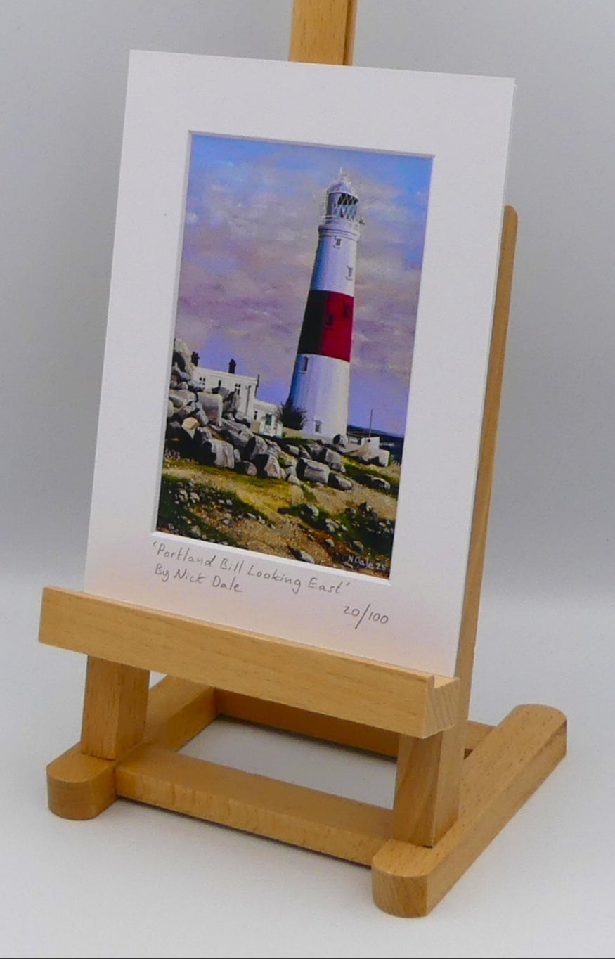 Image of a Small Art Print featuring a copy of the painting 'Portland Bill Looking East' by Nick Dale. The print depicts a view of Portland Bill Lighthouse as seen from the quarry area to the west, looking east. The print is situated on a small easel.