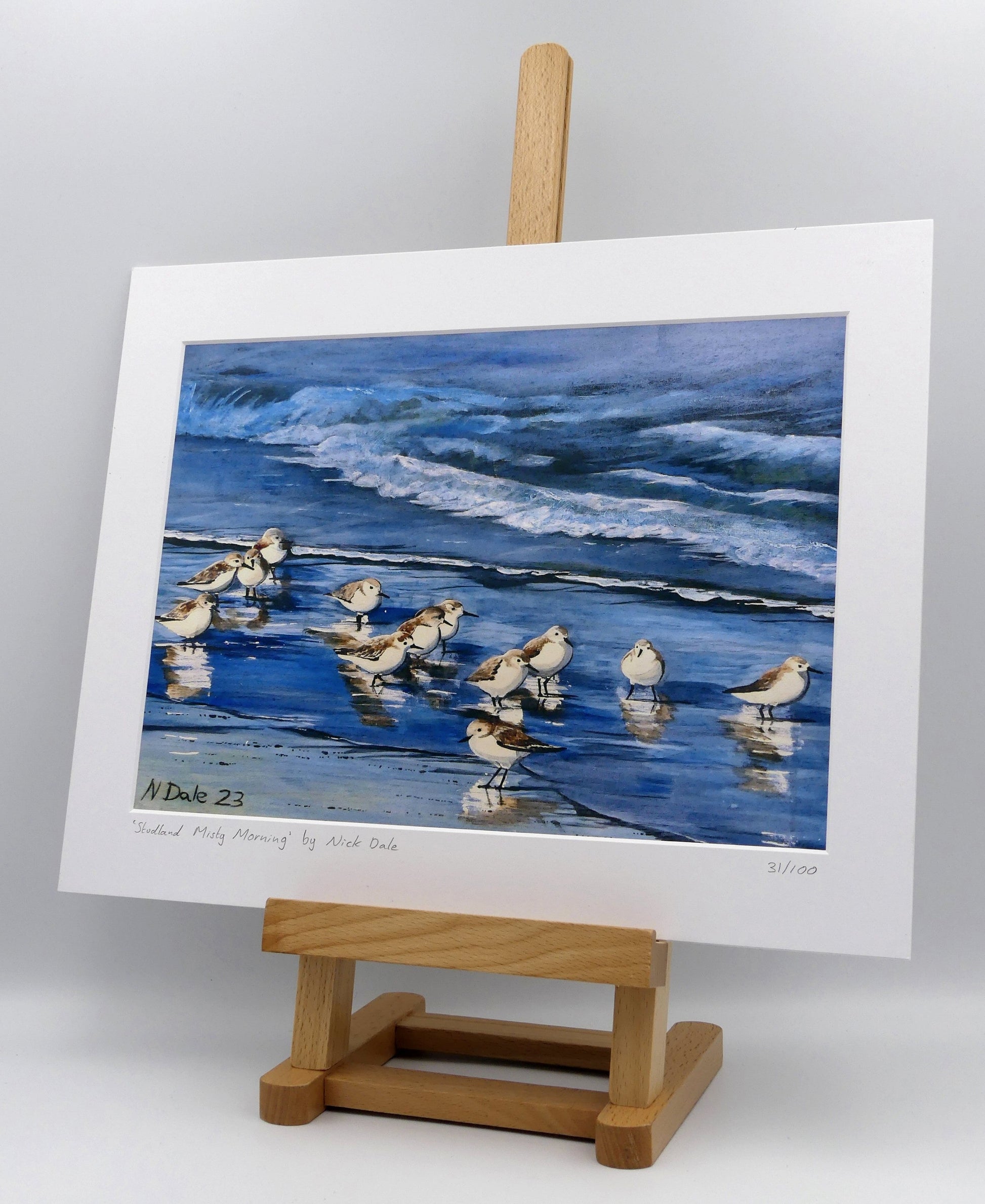 Image of a Medium Art Print featuring a copy of the painting 'Studland Misty Morning' by Nick Dale. The print depicts sanderlings on Studland Beach (Dorset) on a crisp and misty morning. The print is situated on a small easel.