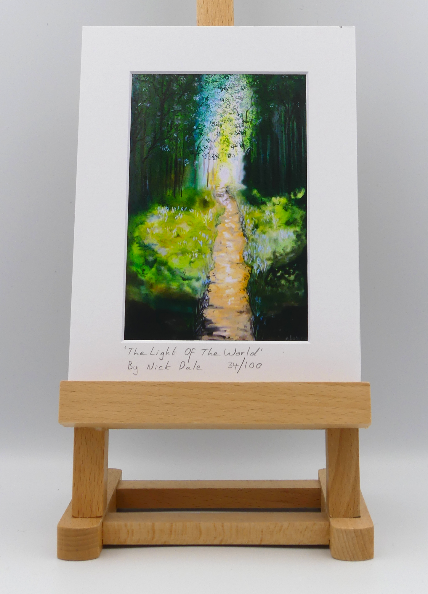 Image of a Small Art Print featuring a copy of the painting 'The Light of the World' by Nick Dale. The print depicts a woodland path at Westonbirt Arboretum (near the town of Tetbury in Gloucestershire) illuminated by the sunlight streaming through the trees. The print is situated on a small easel.