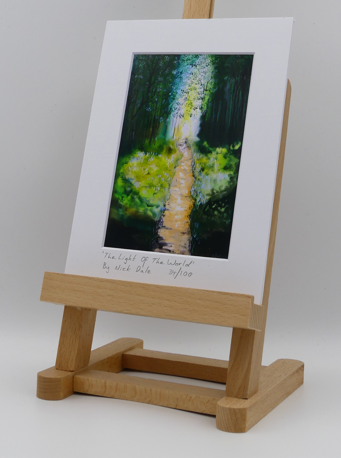 Image of a Small Art Print featuring a copy of the painting 'The Light of the World' by Nick Dale. The print depicts a woodland path at Westonbirt Arboretum (near the town of Tetbury in Gloucestershire) illuminated by the sunlight streaming through the trees. The print is situated on a small easel.