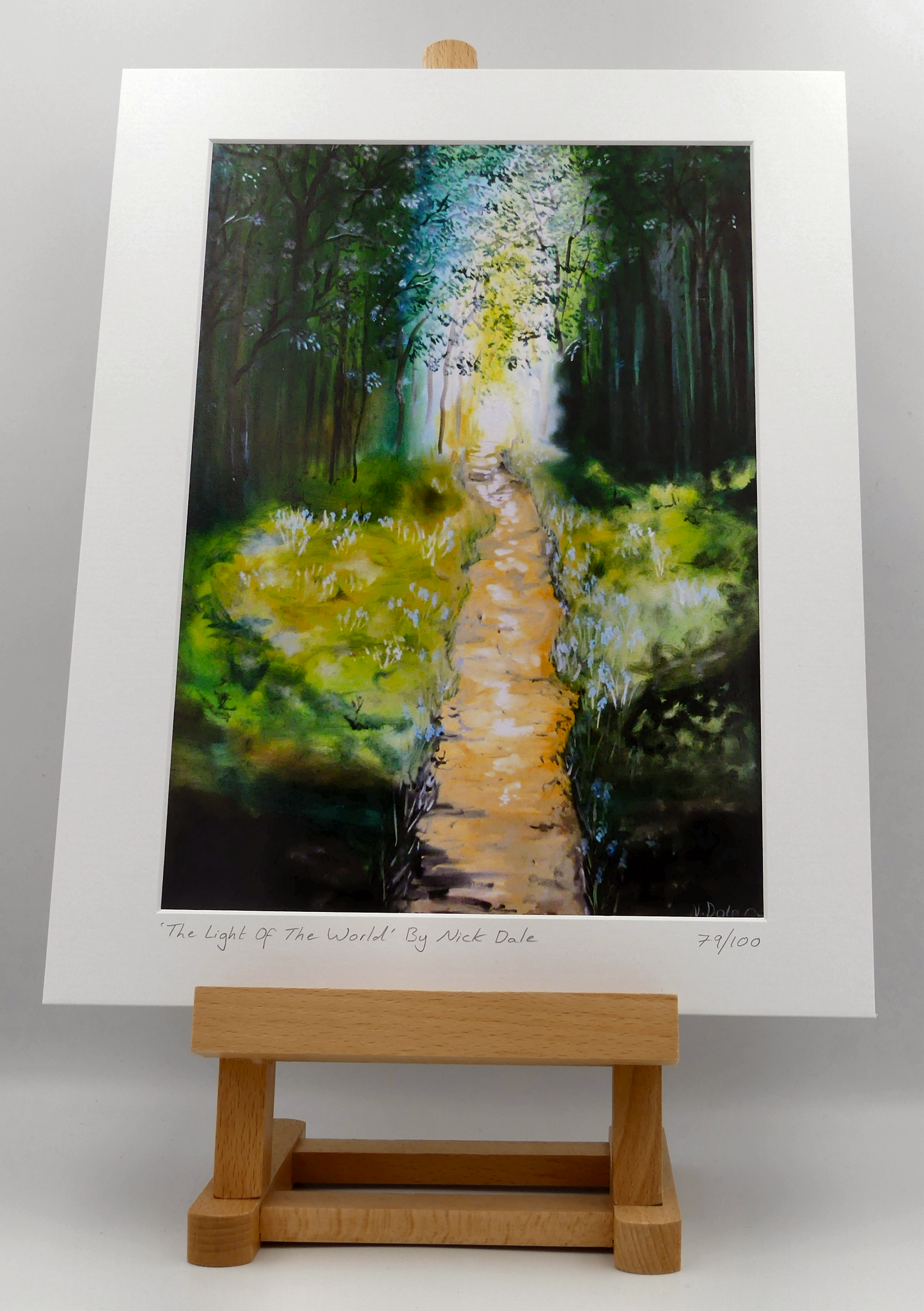 Image of a Medium Art Print featuring a copy of the painting 'The Light of the World' by Nick Dale. The print depicts a woodland path at Westonbirt Arboretum (near the town of Tetbury in Gloucestershire) illuminated by the sunlight streaming through the trees.
The print is situated on a small easel.