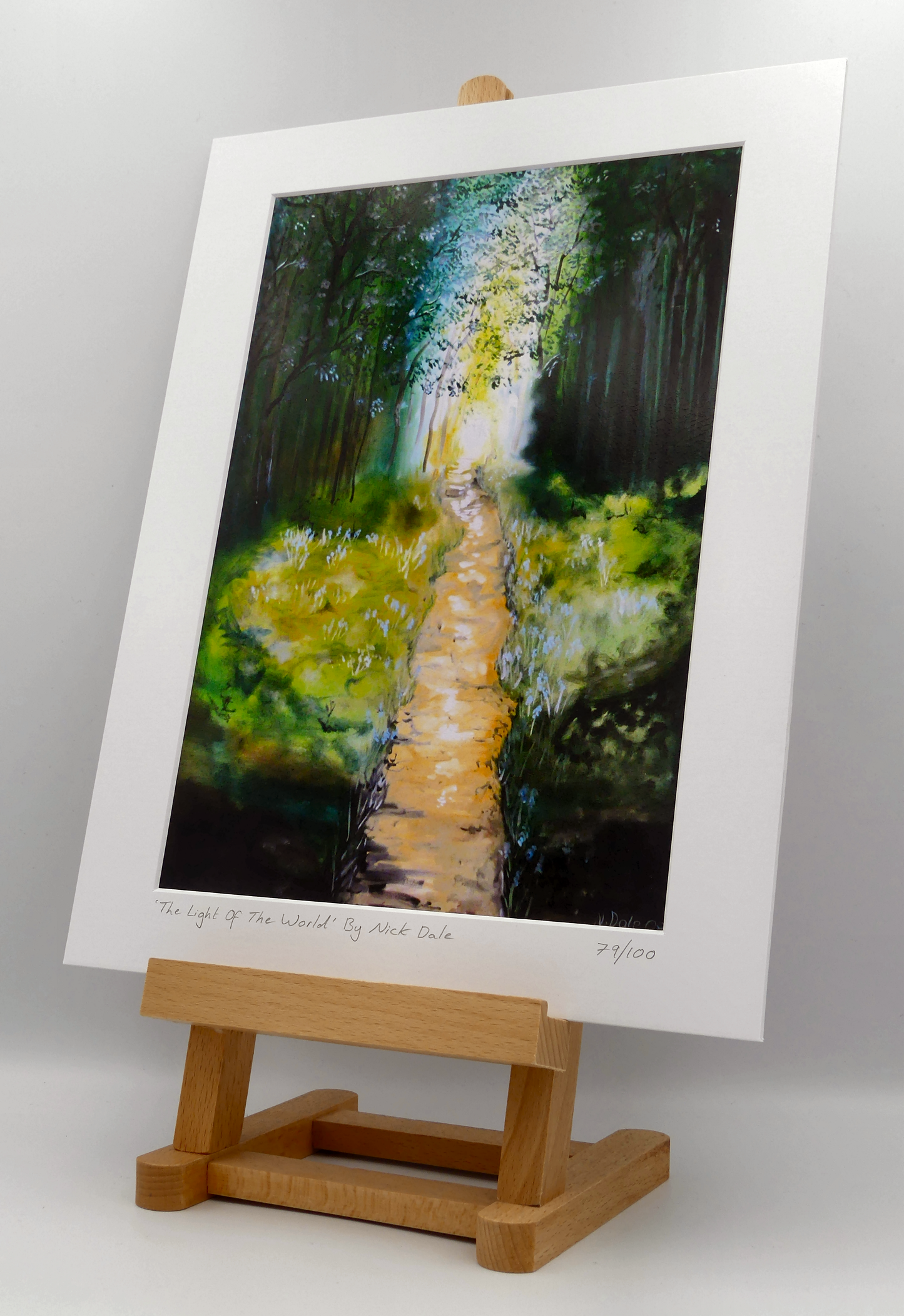 Image of a Medium Art Print featuring a copy of the painting 'The Light of the World' by Nick Dale. The print depicts a woodland path at Westonbirt Arboretum (near the town of Tetbury in Gloucestershire) illuminated by the sunlight streaming through the trees.
The print is situated on a small easel.