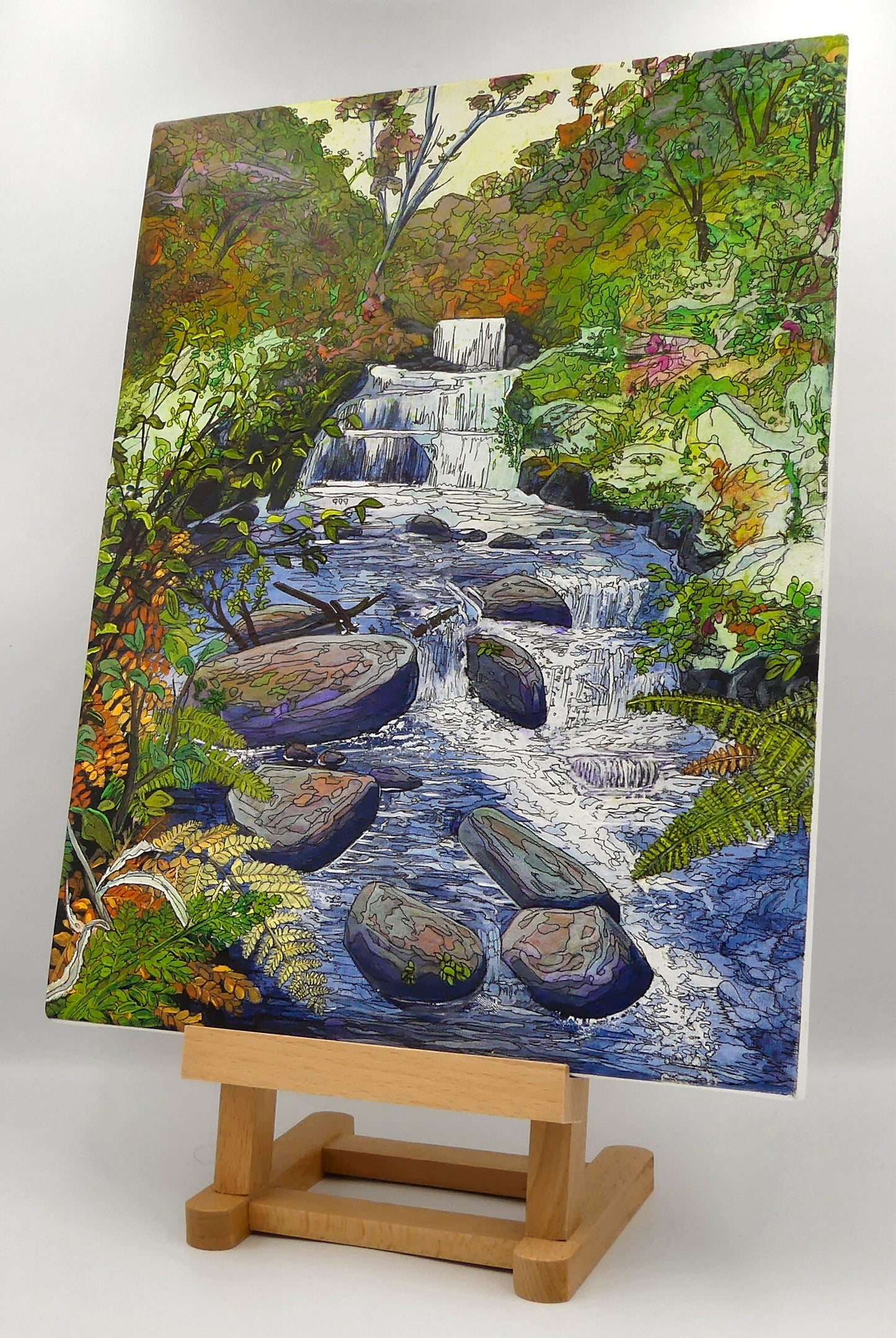 Image of the original painting 'Waterfall' by Nick Dale on an easel. The painting depicts the Hoar Oak Waterfall on the Hoar Oak Water moorland tributary of the East Lyn River at the famous National Trust site of Watersmeet House, Lynmouth, Devon.