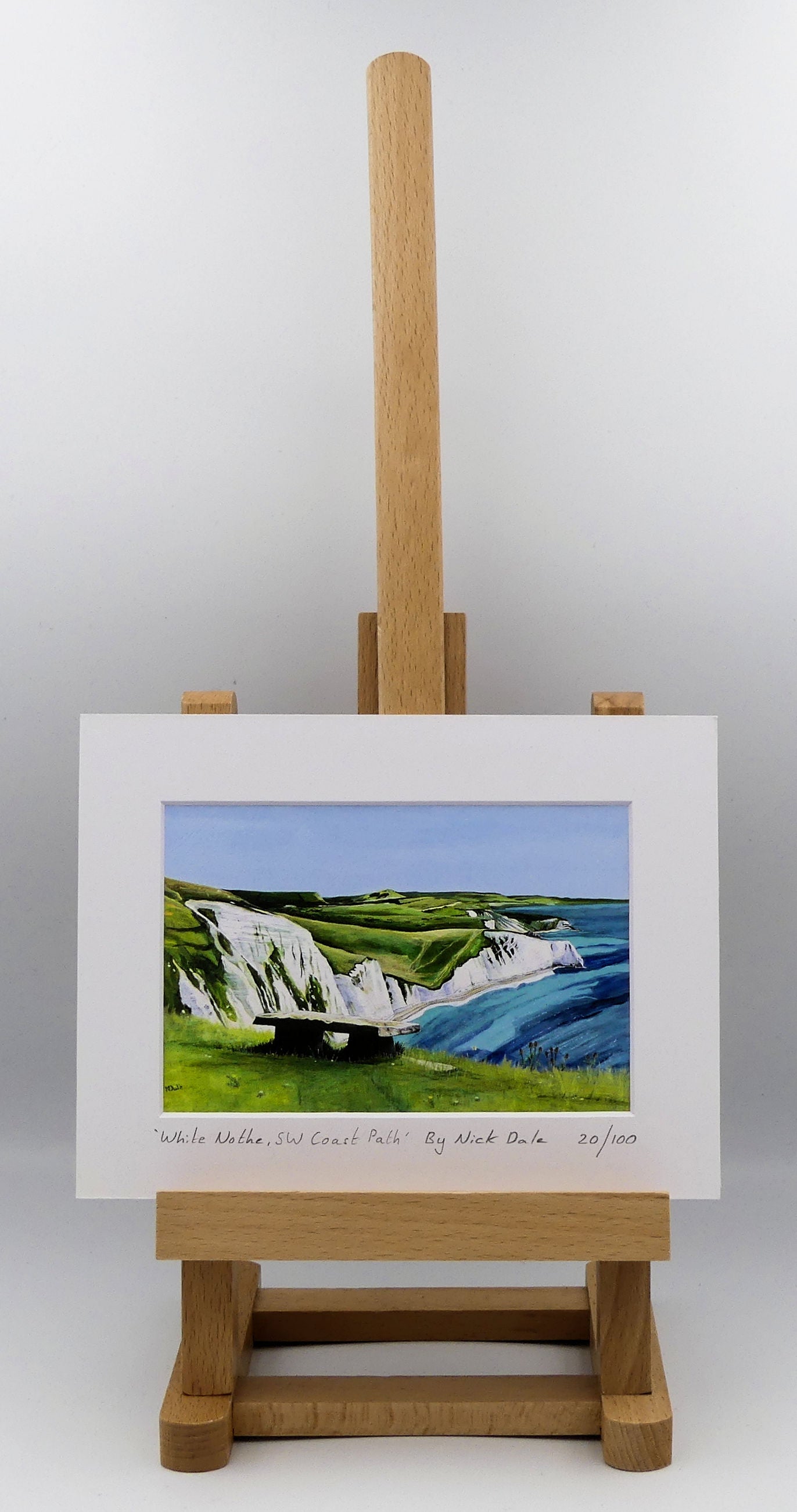Image of a Small Art Print featuring a copy of the painting 'White Nothe, SW Coast Path' by Nick Dale. The print depicts a view along the Jurassic Coast from the White Nothe chalk headland east of Ringstead Bay. The view looks east over Bat's Head, Swyre Head and Durdle Door to St Oswald's Bay & beyond. The print is situated on a small easel.
