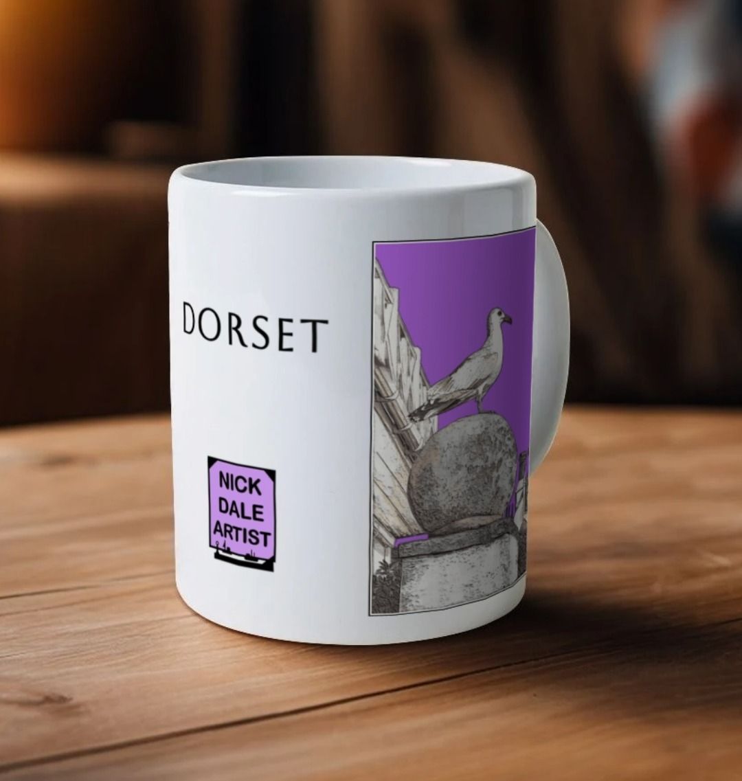 Image of a White Mug on a wooden table featuring a modified copy of the painting 'A View Of The Sea At Lyme Regis' by Nick Dale - this being the 'Purple' version. Image also shows the artist's logo on the mug with the word 'Dorset' written above it. The mug handle is obscured behind the mug. The mug depicts a gull and buildings along Marine Parade, Lyme Regis.