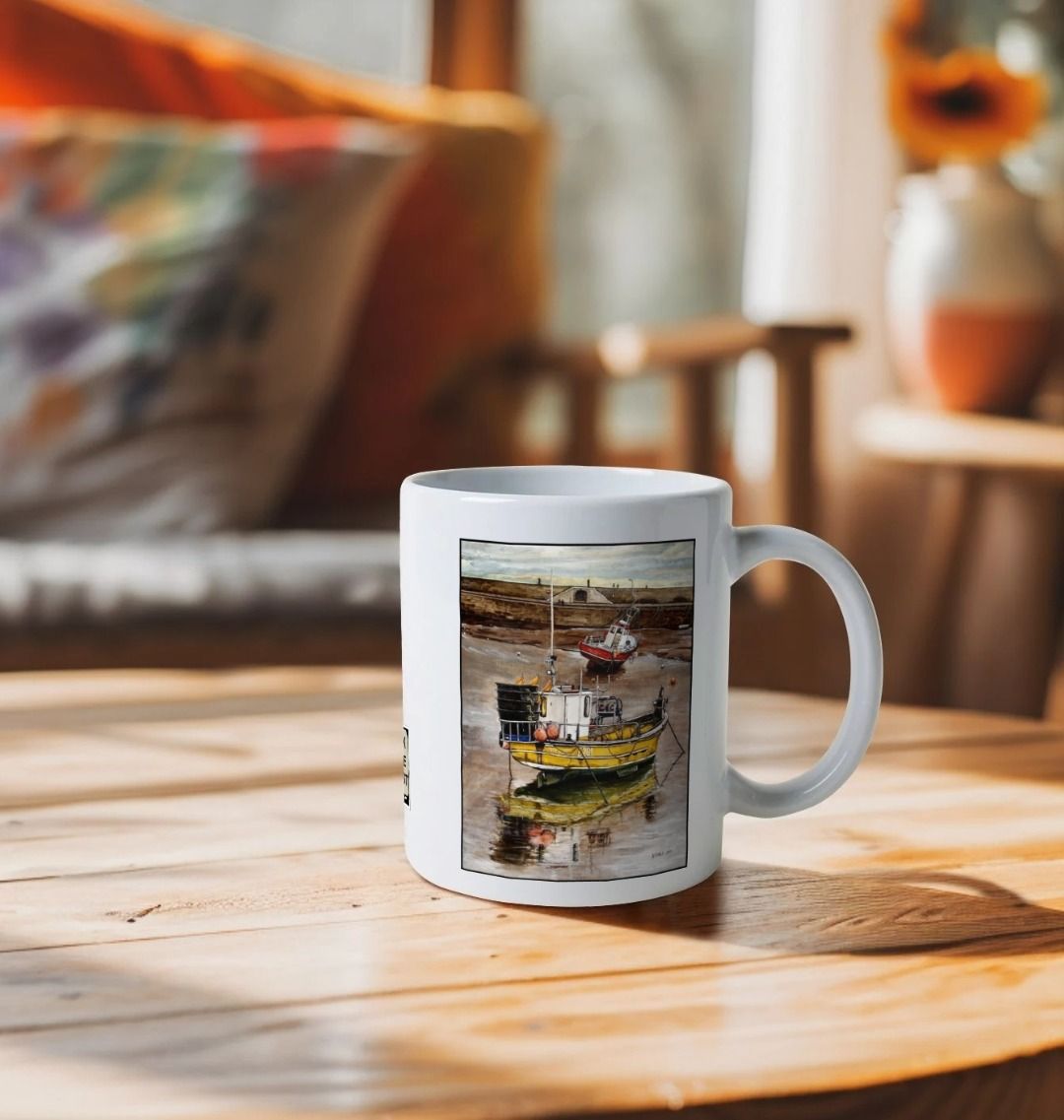 Image of a White Mug on a wooden table featuring a copy of the painting 'Lyme Regis at Low Tide' by Nick Dale. The handle is orientated to the right. The mug depicts a sunset where the fishing vessels rest on the floor of Lyme Regis harbour whilst the tourists enjoy the view from the Cobb.