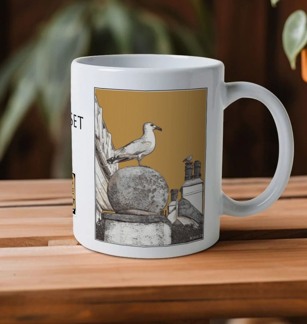 Image of a White Mug on a wooden shelf featuring a modified copy of the painting 'A View Of The Sea At Lyme Regis' by Nick Dale - this being the 'Light Brown' version. The handle is orientated to the right. The mug depicts a gull and buildings along Marine Parade, Lyme Regis.