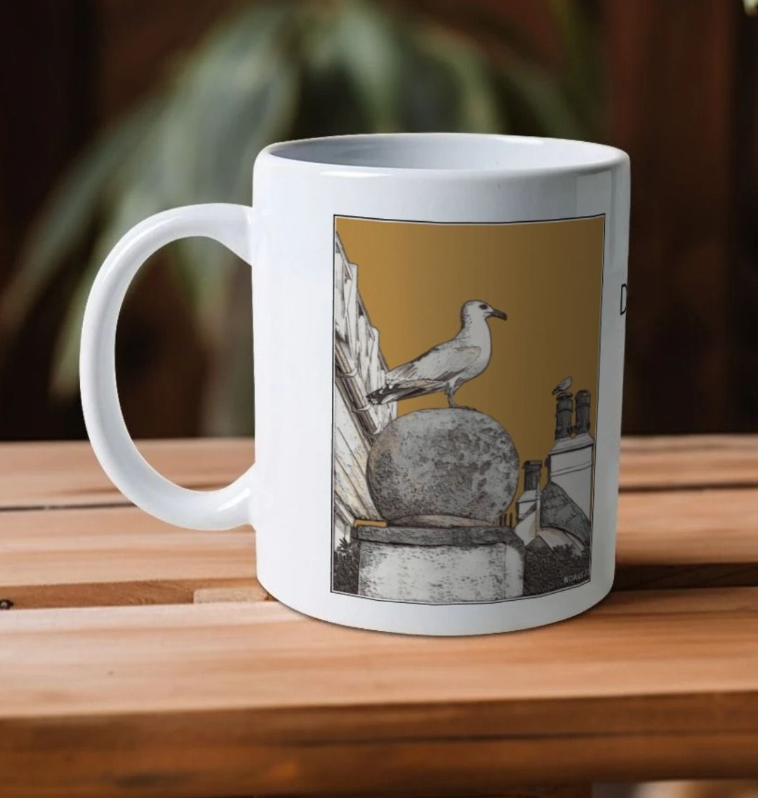 Image of a White Mug on a wooden shelf featuring a modified copy of the painting 'A View Of The Sea At Lyme Regis' by Nick Dale - this being the 'Light Brown' version. The handle is orientated to the left. The mug depicts a gull and buildings along Marine Parade, Lyme Regis.