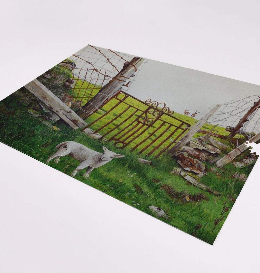 Image of a 1000 Piece Jigsaw Puzzle featuring a copy of the painting 'The Gate' by Nick Dale. As displayed partially completed on a white surface. The jigsaw depicts a lamb in front of an ornamental garden gate reused by a farmer somewhere in North Devon, probably to the south of Valley of Rocks, Lynton. The lamb was observed on Lundy Island, Devon.