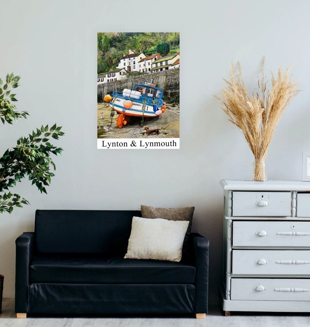 Image of a Large Art Print (A3 size) featuring a copy of the painting 'Lynmouth At Lowest Tide' by Nick Dale, with the words 'Lynton & Lynmouth' written beneath it. As displayed on a wall above a sofa. The print depicts an unusual perspective on the picturesque harbour of Lynmouth (Devon), as seen from the floor of the harbour at low tide. Behind the fishing boat can be seen the characterful harbourside buildings.