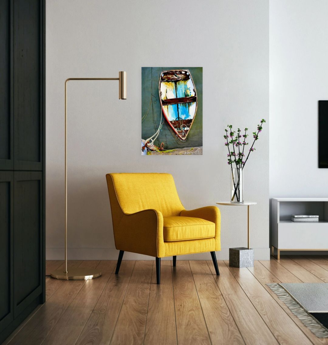 Image of a Large Art Print (A3 size) featuring a copy of the painting 'Good Intentions at Lyme Regis' by Nick Dale. As displayed on a wall next to a chair. The print depicts a small wooden rowing boat tied up in Lyme Regis harbour, Dorset.