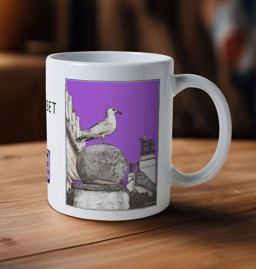 Image of a White Mug on a wooden table featuring a modified copy of the painting 'A View Of The Sea At Lyme Regis' by Nick Dale - this being the 'Purple' version. The handle is orientated to the right. The mug depicts a gull and buildings along Marine Parade, Lyme Regis.