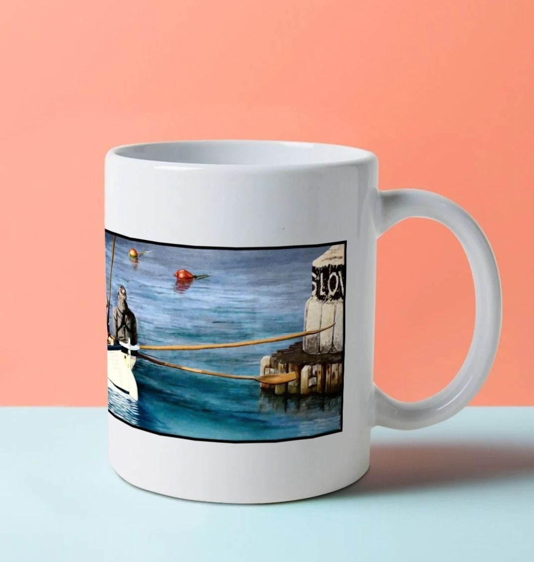 Image of a White Mug on a blue worksurface featuring a copy of the painting 'The Return to Base at Lyme Regis' by Nick Dale. The handle is orientated to the right. The mug depicts the crew of a gig rowing boat returning to Lyme Regis Harbour to take a well-earned rest.