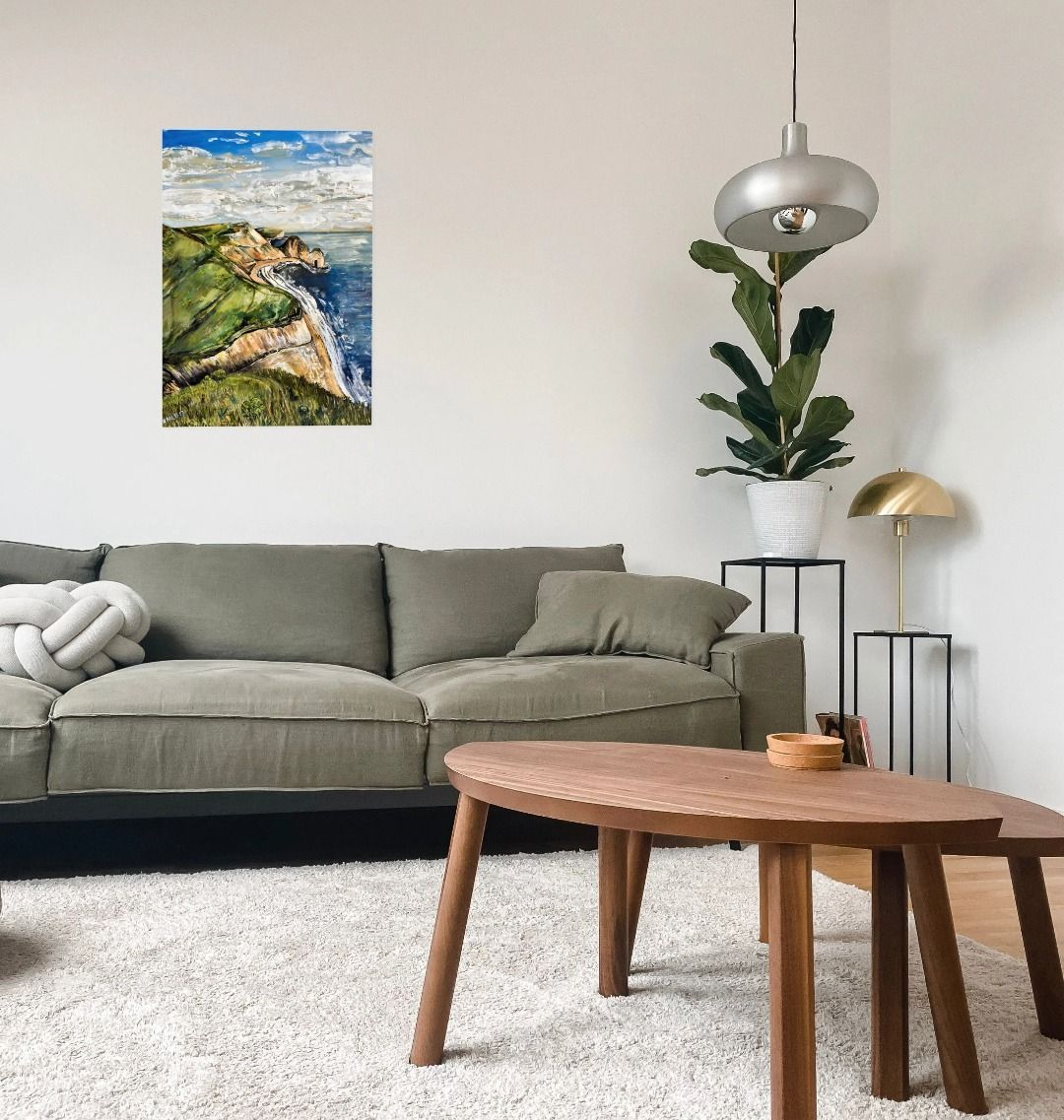Image of a Large Art Print (A3 size) featuring a copy of the painting 'Durdle Door From The West' by Nick Dale. As displayed on a wall above a sofa. The print depict a view along the Jurassic Coast to the famous Dorset limestone arch landmark, as seen from the coastal path to the west.