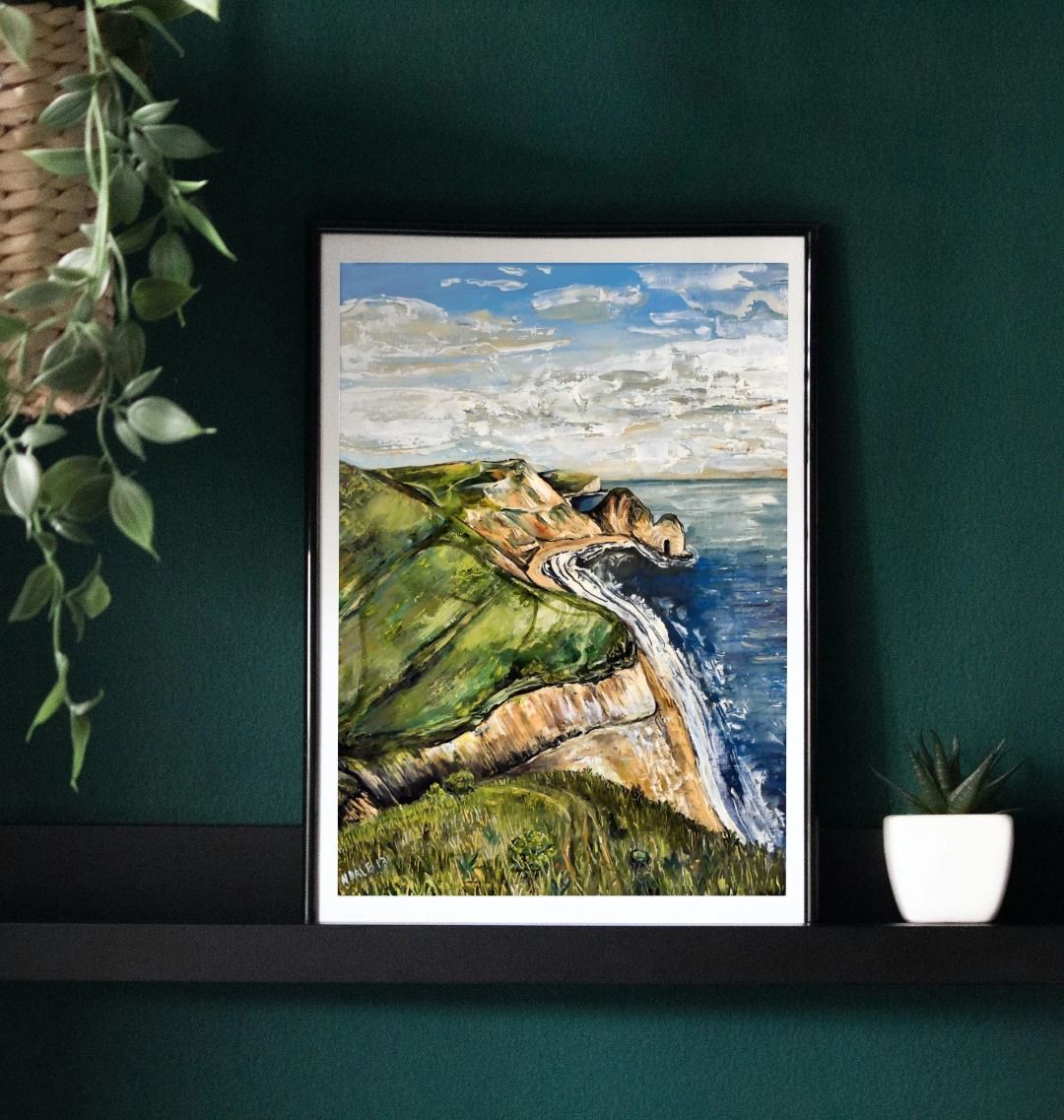 Image of a Large Art Print (A3 size) featuring a copy of the painting 'Durdle Door From The West' by Nick Dale. As displayed in a frame on a shelf. The print depict a view along the Jurassic Coast to the famous Dorset limestone arch landmark, as seen from the coastal path to the west.