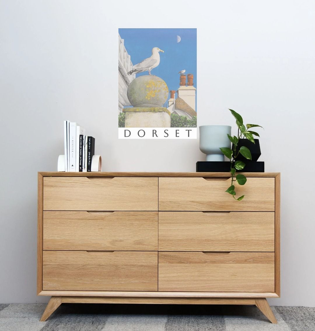 Image of a Large Art Print (A3 size) featuring a copy of the painting 'A View Of The Sea At Lyme Regis' by Nick Dale; as displayed on a wall above a dresser. The print depicts a gull and buildings along Marine Parade, Lyme Regis.