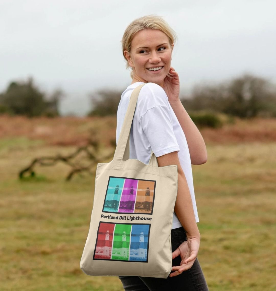 Image of a female model carrying a Natural Tote Bag featuring 6 digitally modified versions of the painting 'Rothko's Work Experience At Portland Bill Lighthouse' by Nick Dale, with the words 'Portland Bill Lighthouse' written between the lighthouse images that have been divided into 2 groups of 3 versions each. The bag depicts what might happen if the abstract painter Mark Rothko worked at Portland Bill Lighthouse in Portland, Dorset.