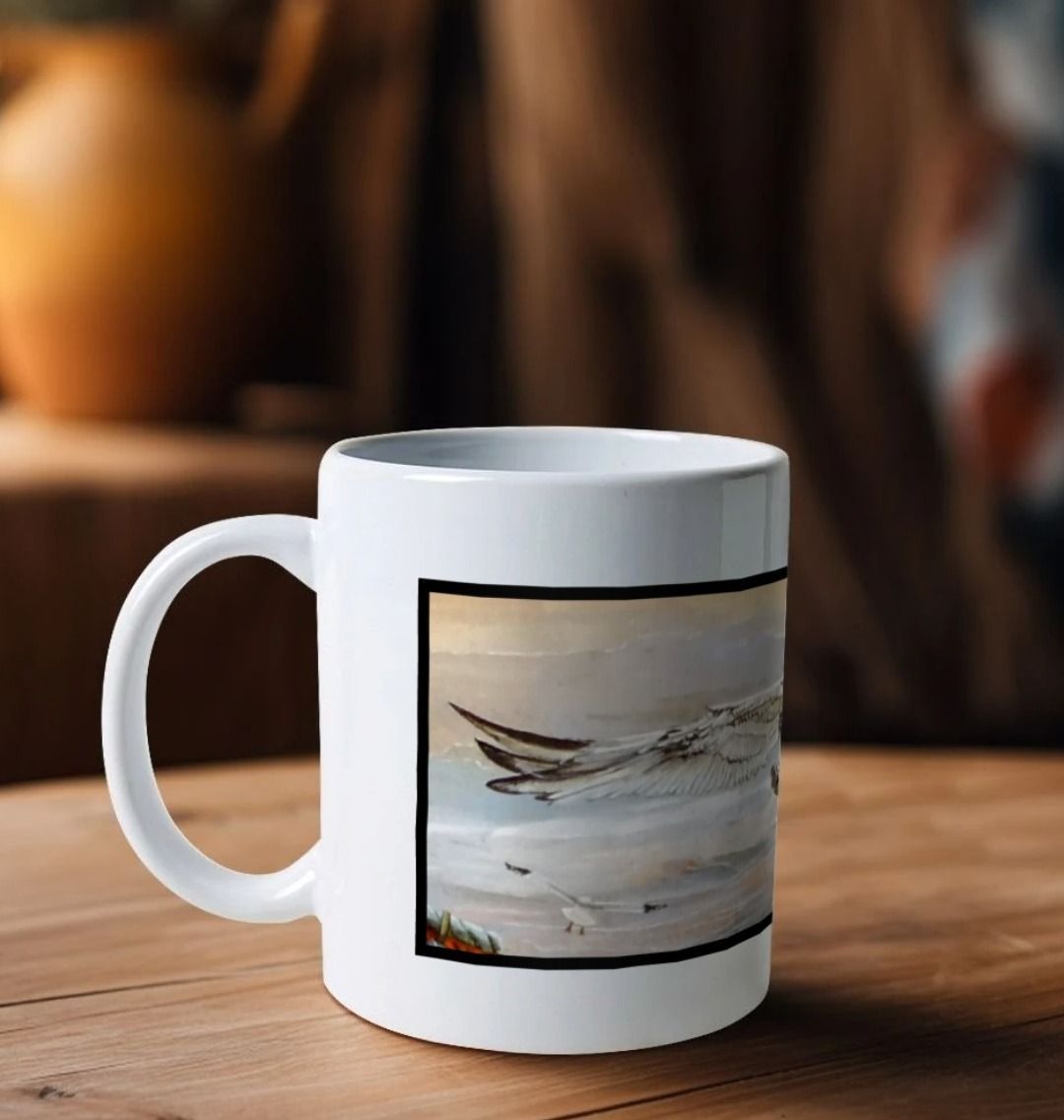 Image of a White Mug on a wooden table featuring a copy of a detail from the painting 'The Gordian Knot At Lyme Regis' by Nick Dale. The handle is orientated to the left. The mug depicts a gull flying over the Cobb at Lyme Regis, Dorset. The title refers to the jumbled pile of fishing equipment sitting on the quayside visible in the original painting.