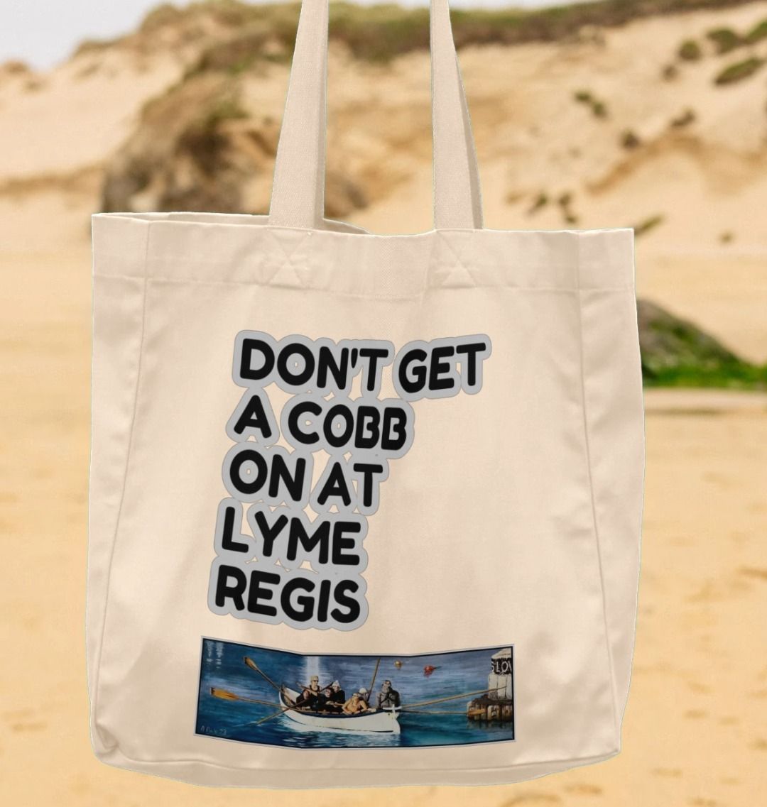 Image of a suspended Natural Shopper Tote Bag featuring a copy of the painting 'The Return to Base at Lyme Regis' by Nick Dale with the slogan 'Don't Get A Cobb On At Lyme Regis' written above it. The bag depicts the crew of a gig rowing boat returning to Lyme Regis Harbour to take a well-earned rest.