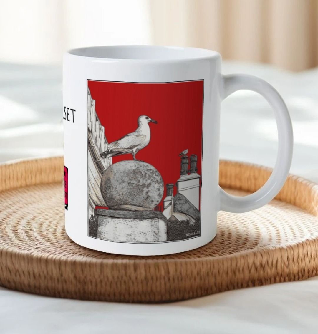 Image of a White Mug on a tray on a bed featuring a modified copy of the painting 'A View Of The Sea At Lyme Regis' by Nick Dale - this being the 'Red' version. The handle is orientated to the right. The mug depicts a gull and buildings along Marine Parade, Lyme Regis.