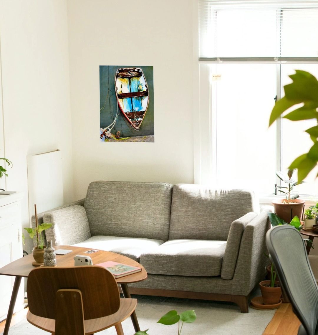 Image of a Large Art Print (A3 size) featuring a copy of the painting 'Good Intentions at Lyme Regis' by Nick Dale. As displayed on a wall above a sofa. The print depicts a small wooden rowing boat tied up in Lyme Regis harbour, Dorset.