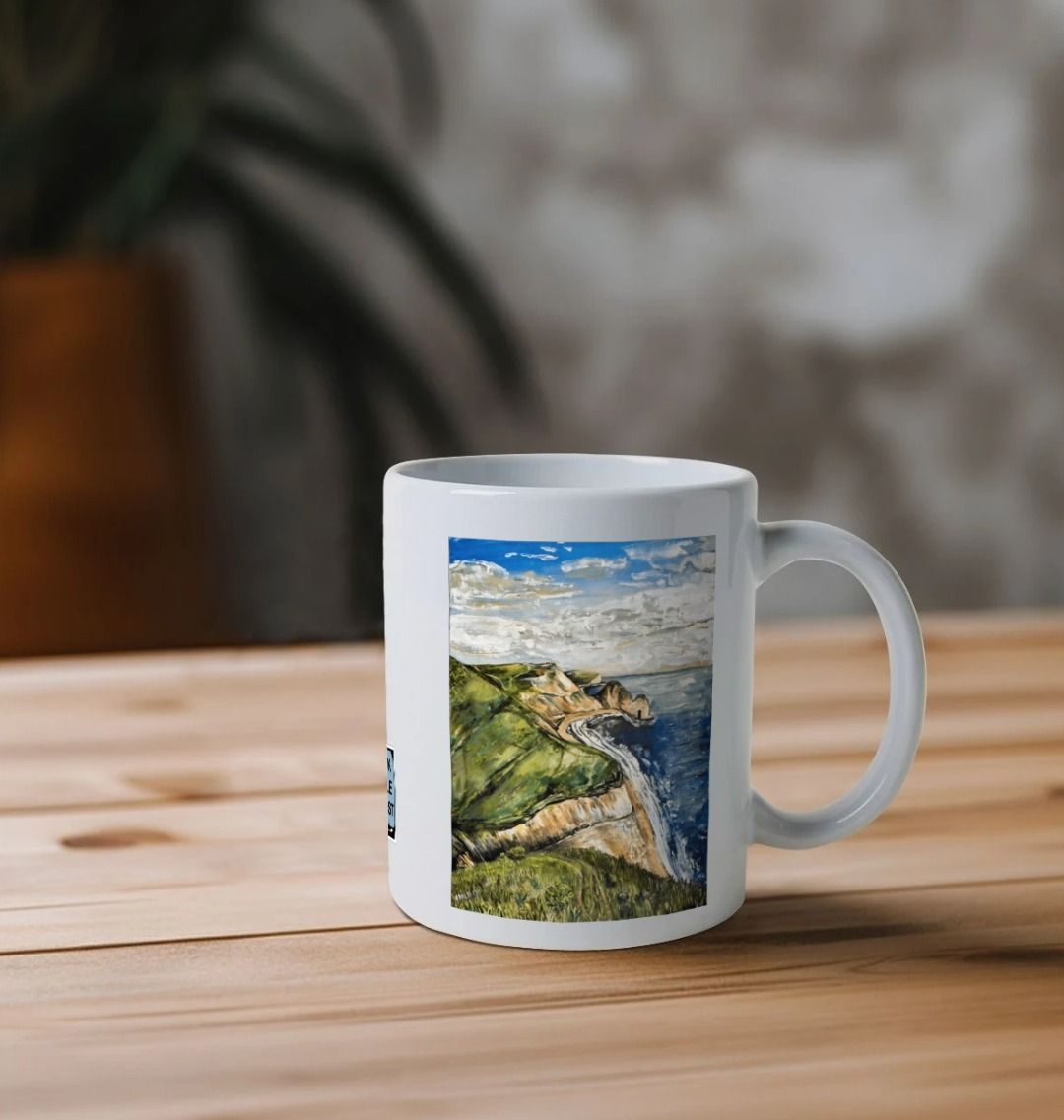 Image of a White Mug on a table featuring a copy of the painting 'Durdle Door From The West' by Nick Dale. The handle is orientated to the right. The mug depicts a view along the Jurassic Coast to the famous Dorset limestone arch landmark, as seen from the coastal path to the west.