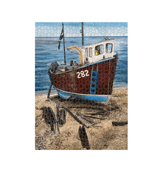 Image of a 1000 Piece Jigsaw Puzzle featuring a copy of the painting 'Relaxing Beer' by Nick Dale. The jigsaw depicts a fishing boat beached at Beer, Devon. The wood is laid under the boats to aid in their winching up the shingle beach.