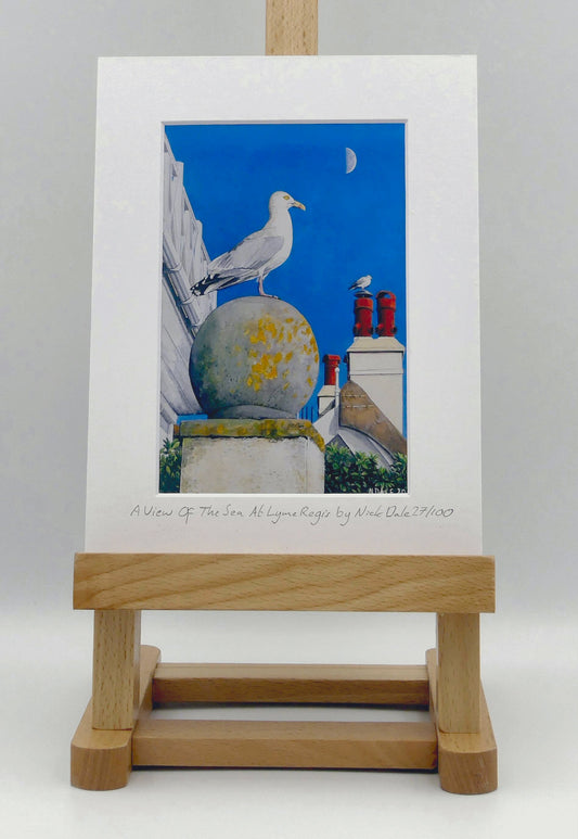 Image of Small Art Print featuring a copy of the painting 'A View Of The Sea At Lyme Regis' by Nick Dale. The print depicts a gull and buildings along Marine Parade, Lyme Regis. The print is situated on a small easel.