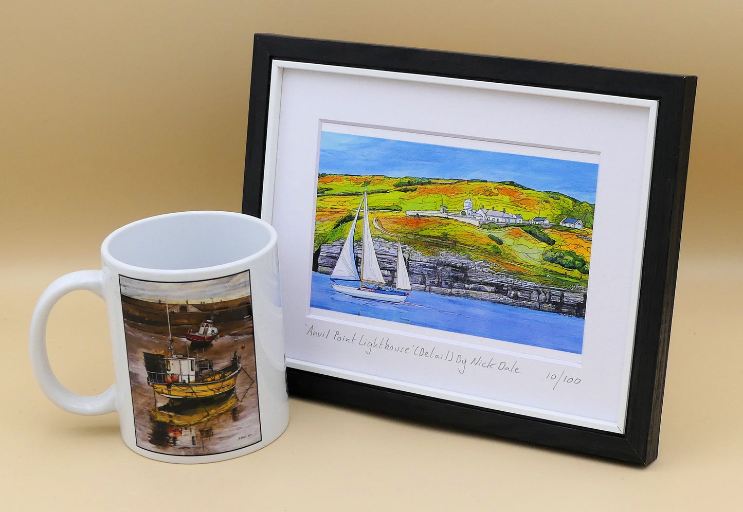 Image of a Small Art Print featuring a copy of the painting 'Anvil Point Lighthouse' by Nick Dale. The print depicts the part of the original painting showing the Anvil Point Lighthouse at Durlston Country Park, Swanage. Based on the view from the paddle-steamer Waverley. The print is situated in a black frame next to a mug.