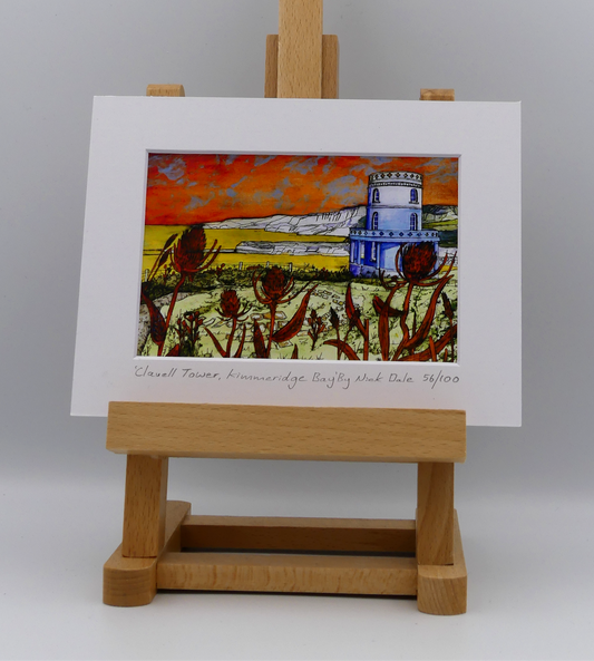 Image of a Small Art Print featuring a copy of the painting 'Clavell Tower, Kimmeridge Bay' by Nick Dale. The scene depicts Clavell Tower (which is also known as the Clavell Folly or the Kimmeridge Tower) situated on the cliffs overlooking Kimmeridge Bay on the Isle of Purbeck, Dorset. The tower; which was built in 1830, is seen in its current position with the original footings visible in the foreground after the tower was moved further back from the cliff in 2006.  The print is situated on a small  easel.