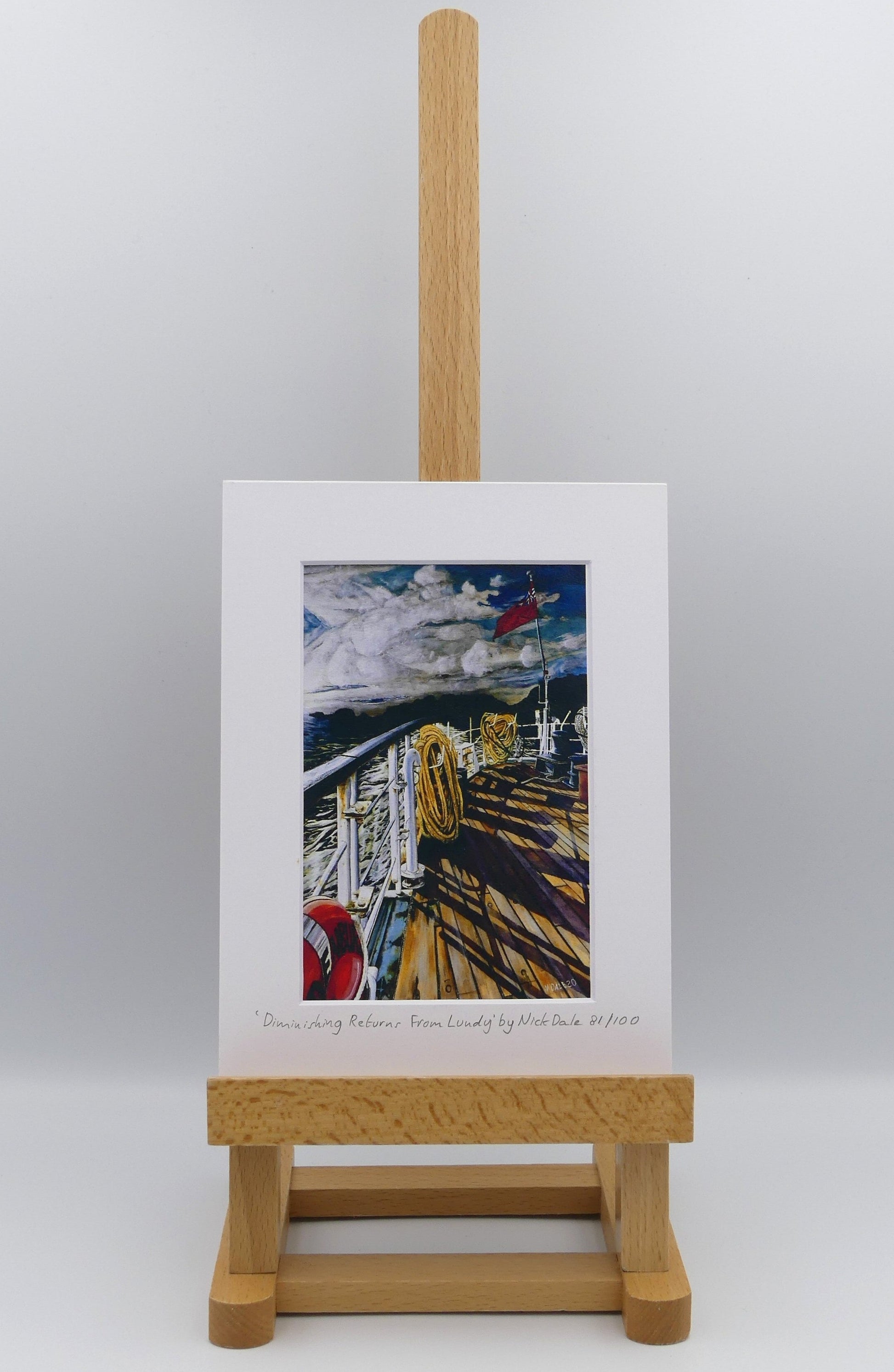 Image of Small Art Print featuring a copy of the painting 'Diminishing Returns From Lundy' by Nick Dale. The print depicts the stern of the ship MS Oldenburg as it returns to the mainland from Lundy Island, Devon. As the sun goes down it casts long shadows on the deck. whilst the flag flutters in the breeze. The Silhouette of the island can be seen diminishing into the background. The print is situated on a small easel.