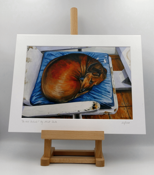 Image of a Medium Art Print featuring a copy of the painting 'Do Not Disturb' by Nick Dale. The print depicts a miniature dachshund dog curled up on a favourite seat. Its gaze clearly indicates that it is not keen on being evicted from its current location and slumbering state. The print is situated on a small easel.