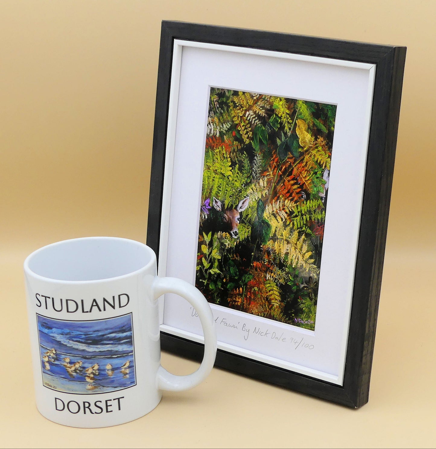 Image of a Small Art Print featuring a copy of the painting 'Doe And Fawn' by Nick Dale. The print depicts a Row Deer doe and fawn hiding in the dense undergrowth with only their heads visible. The print is situated in a black frame next to a mug.