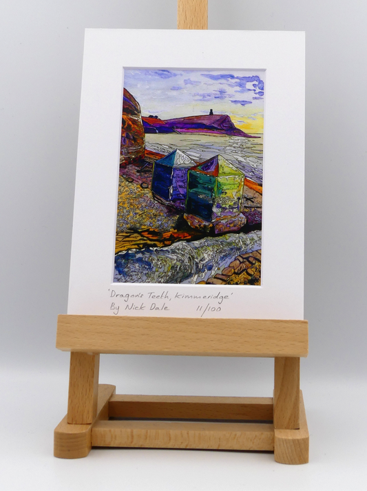 Image of a Small Art Print featuring a copy of the painting 'Dragon's Teeth, Kimmeridge' by Nick Dale. The scene depicts two surviving dragon's teeth anti-tank defences on the beach at Kimmeridge Bay, Dorset. Beyond them can be seen Clavell Tower on the cliff top. The Gaulter Gap forms a relatively easy route off the beach to the cliffs above for any invading force so it was blocked with dragon's teeth and a concrete pillbox during World War II.  The print is situated on a small easel.