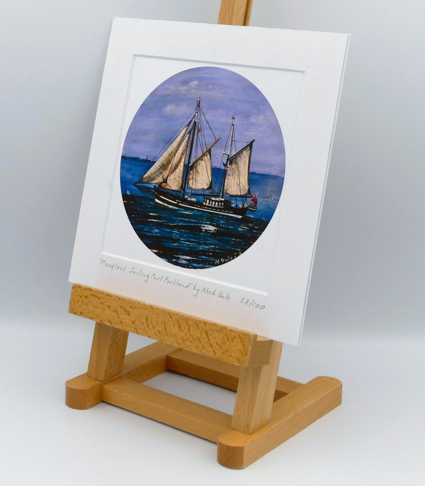 Image of Square Medium Art Print featuring a copy of the painting 'Moonfleet Sailing Past Portland' by Nick Dale. The print depicts the tall ship Moonfleet sailing past the western coast of Portland, Dorset. As observed from Ringstead Beach. The print is situated on a small easel.