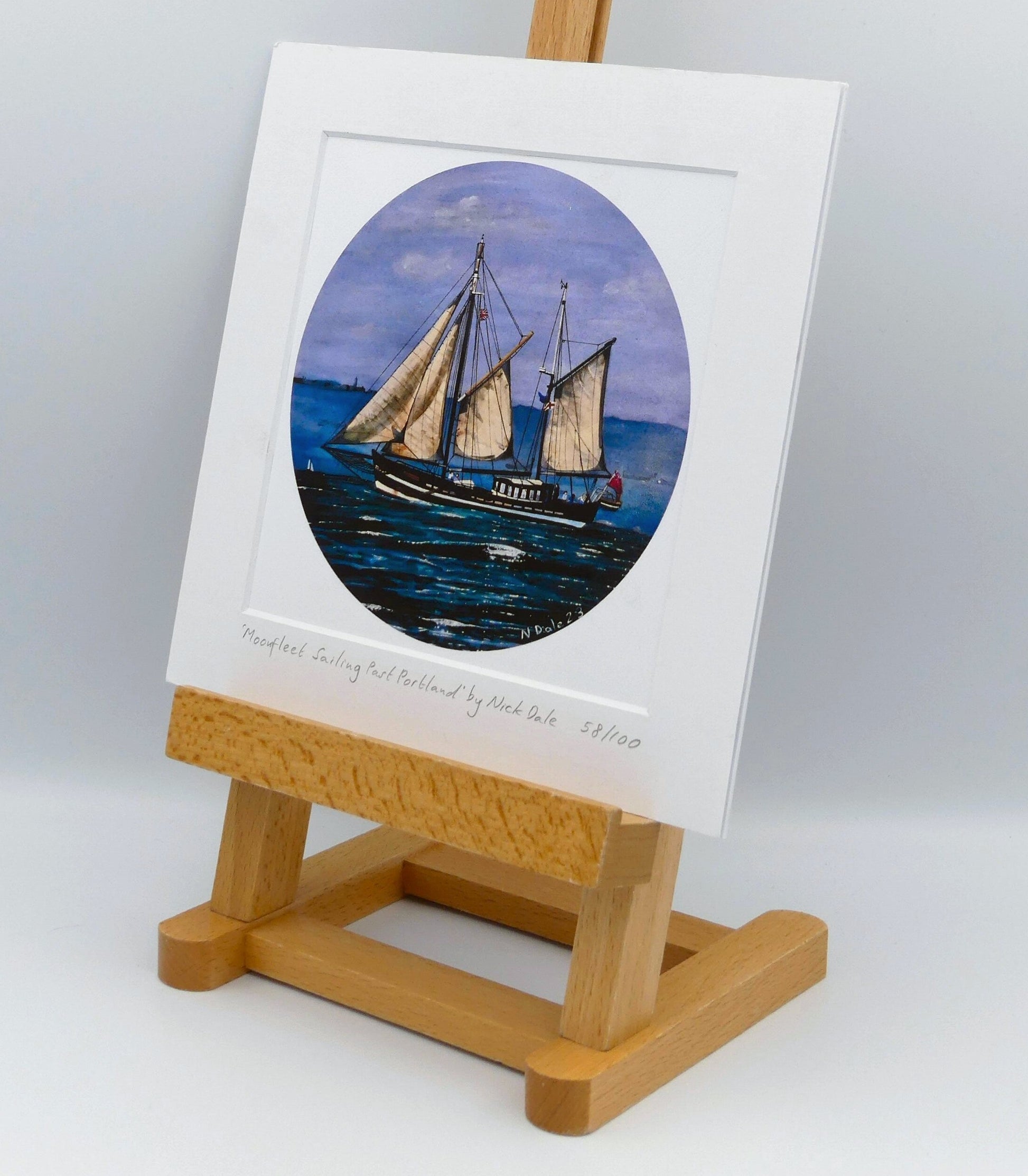 Image of Square Medium Art Print featuring a copy of the painting 'Moonfleet Sailing Past Portland' by Nick Dale. The print depicts the tall ship Moonfleet sailing past the western coast of Portland, Dorset. As observed from Ringstead Beach. The print is situated on a small easel.