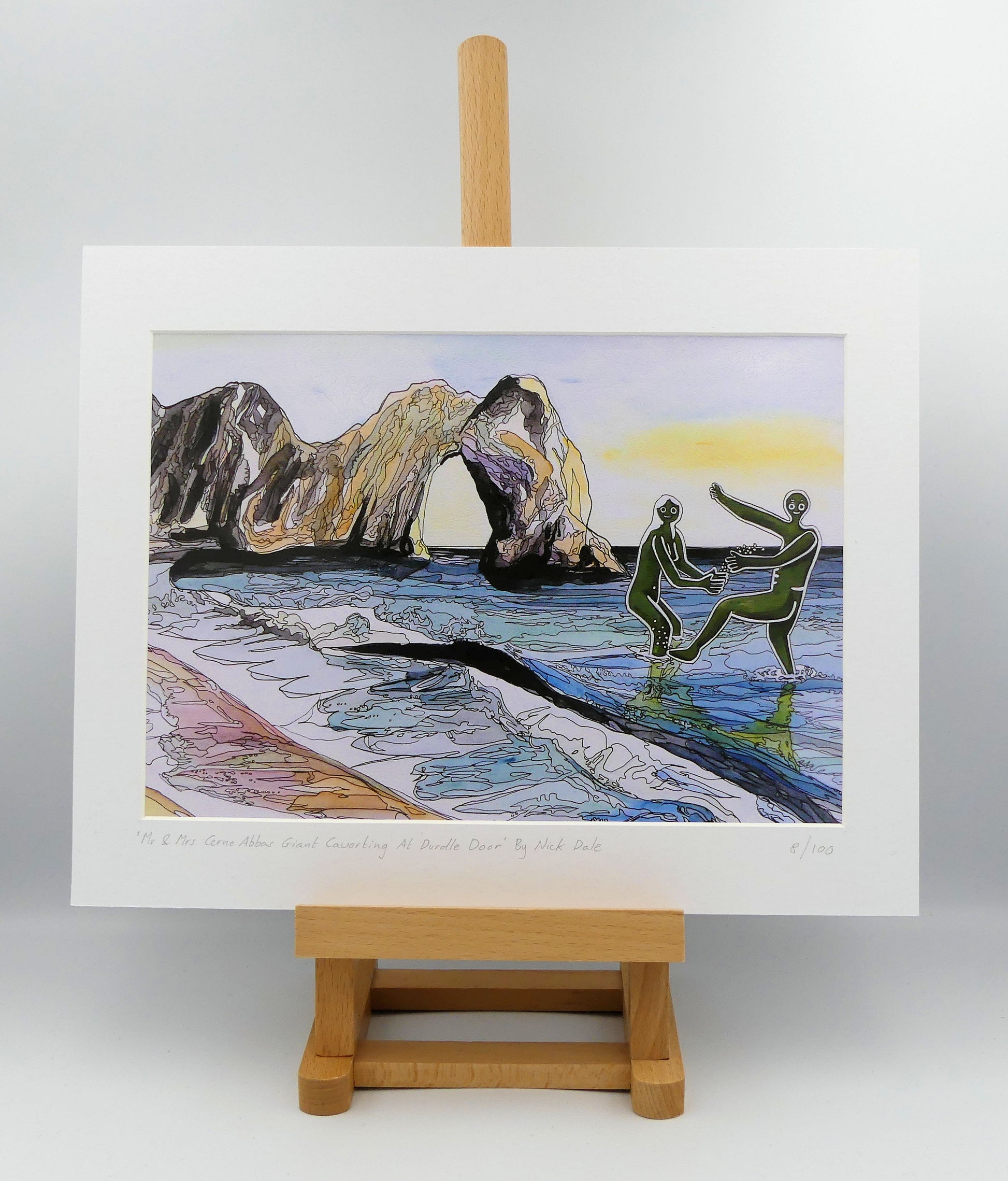 Image of a Medium Art Print featuring a copy of the painting 'Mr & Mrs Cerne Abbas Giant Cavorting At Durdle Door' by Nick Dale. The scene imagines the future Mr & Mrs Cerne Abbas Giant's first date at Durdle Door; where they cavort in the water in front of the famous Dorset landmark. The print is situated on a small easel.