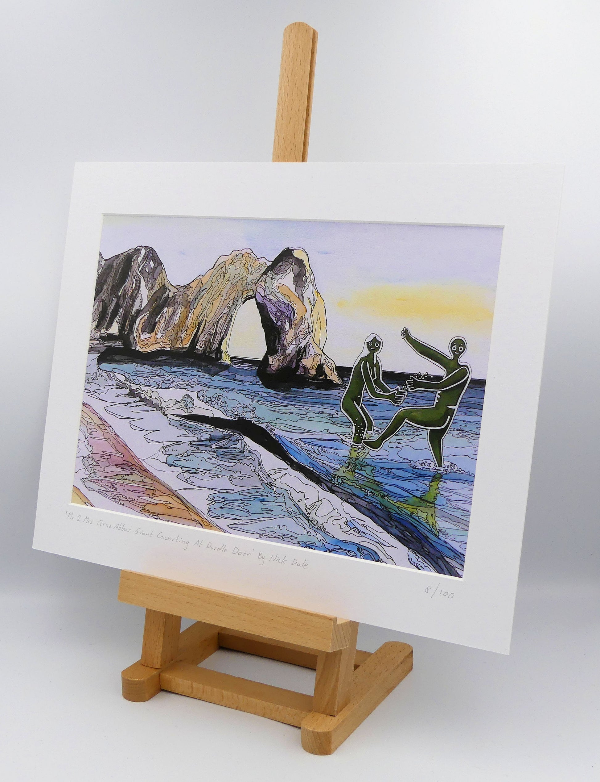Image of a Medium Art Print featuring a copy of the painting 'Mr & Mrs Cerne Abbas Giant Cavorting At Durdle Door' by Nick Dale. The scene imagines the future Mr & Mrs Cerne Abbas Giant's first date at Durdle Door; where they cavort in the water in front of the famous Dorset landmark. The print is situated on a small easel.