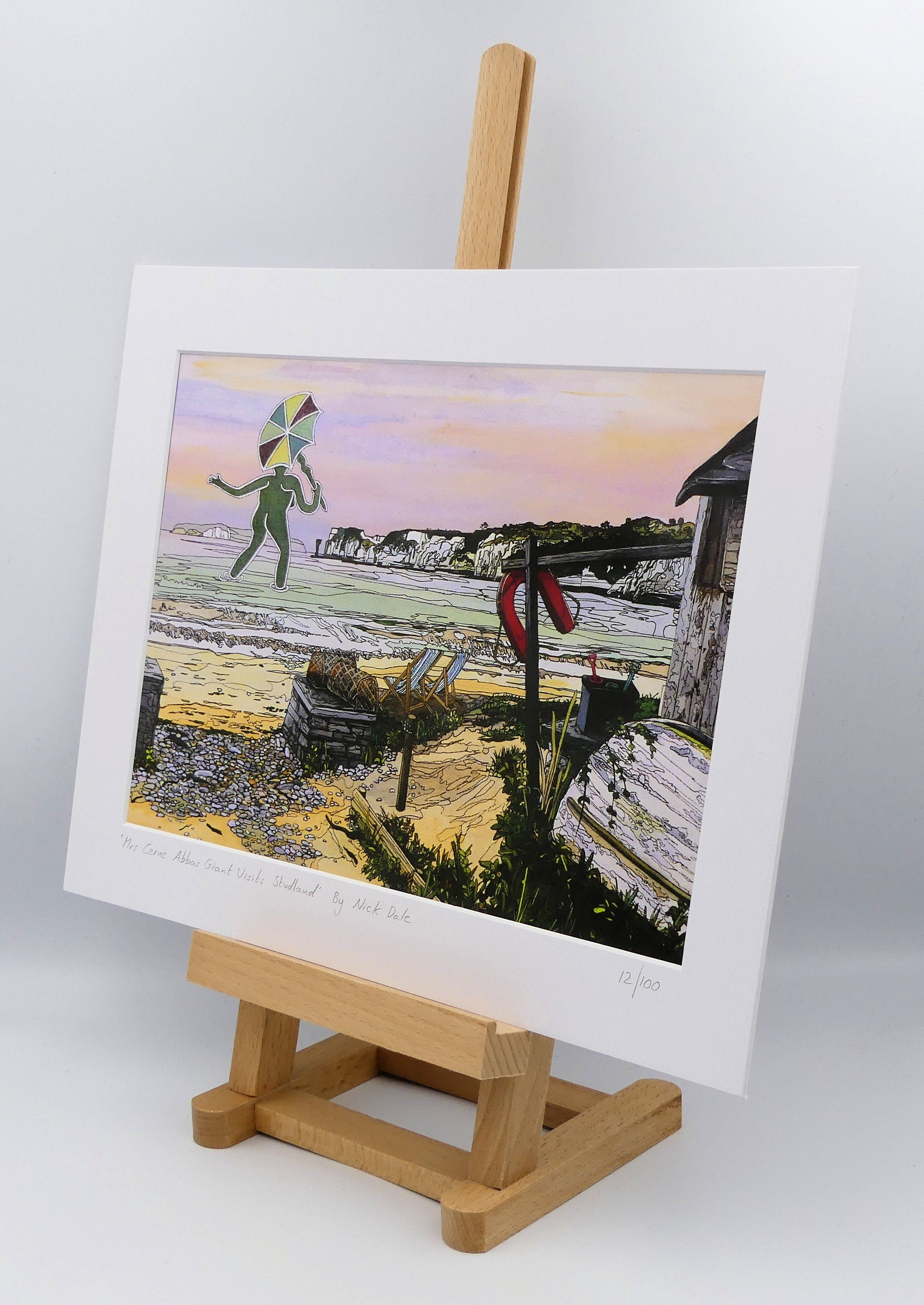 Image of a Medium Art Print featuring a copy of the painting 'Mrs Cerne Abbas Giant Visits Studland' by Nick Dale. The print imagines the Cerne Abbas Giant's wife visiting the seaside at Studland Beach; with Old Harry Rocks and the Isle of Wight in the distance. The print is situated on a small easel.
